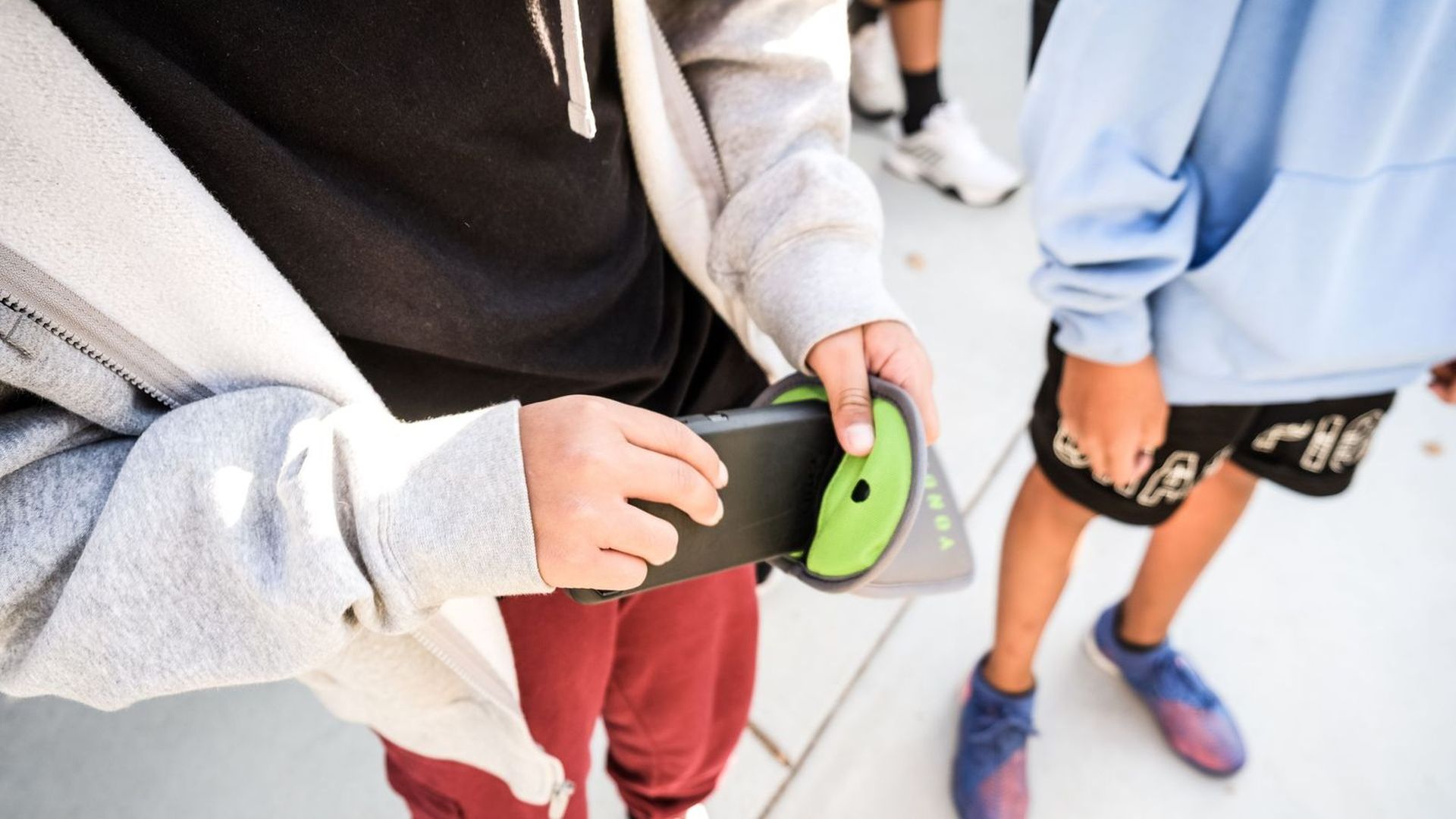 kid puts phone inside a lime green pouch