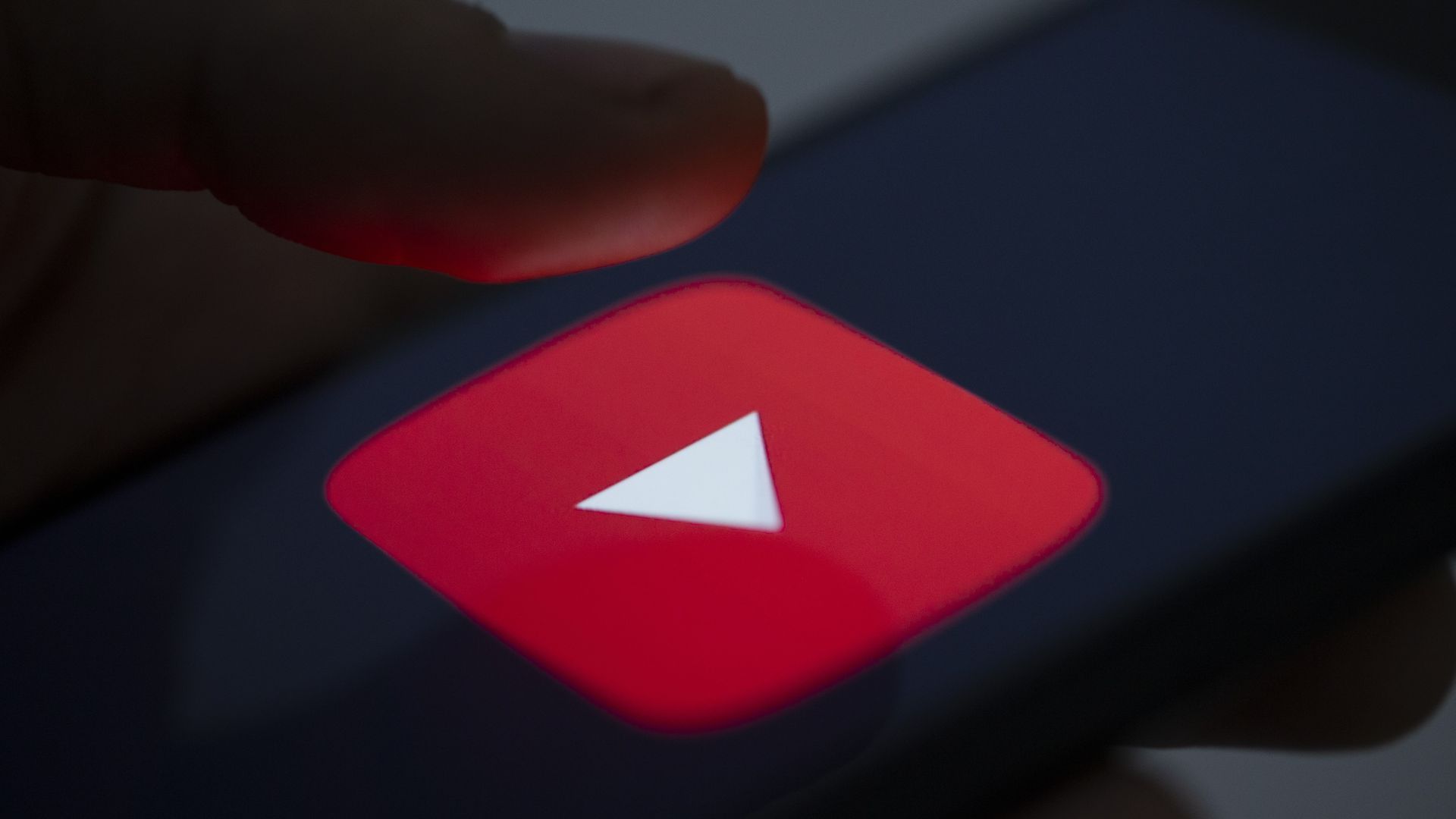 An image of a finger pressing a YouTube button on a smartphone.