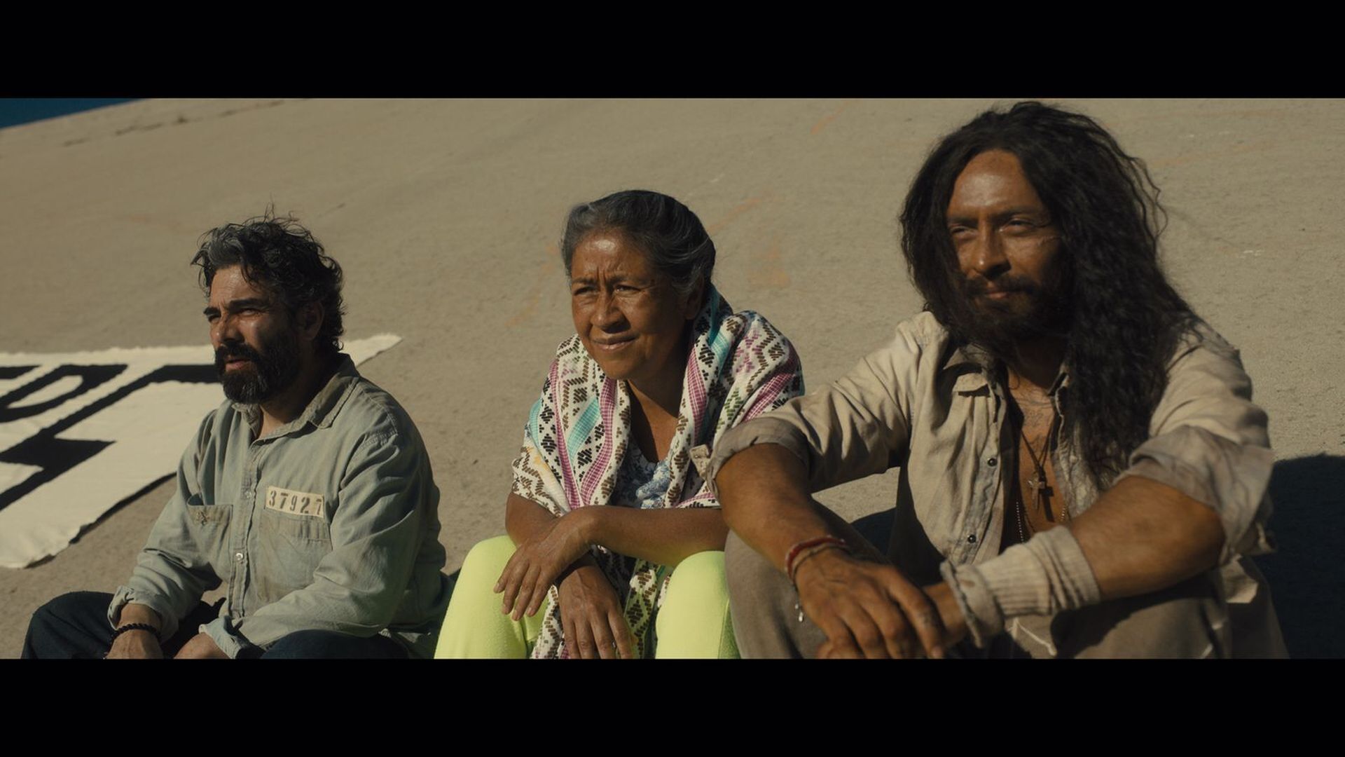 A screenshot of a movie where three people sit on a roof