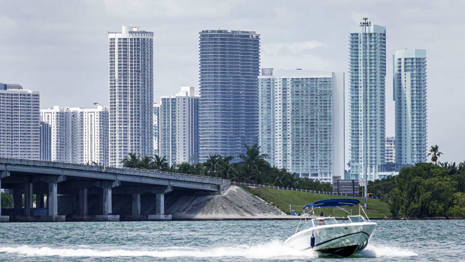 Miami Beach, Florida, Biscayne Bay water, Edgewater Midtown high rise skyline with Julia Tuttle Causeway Bridge with speed boat