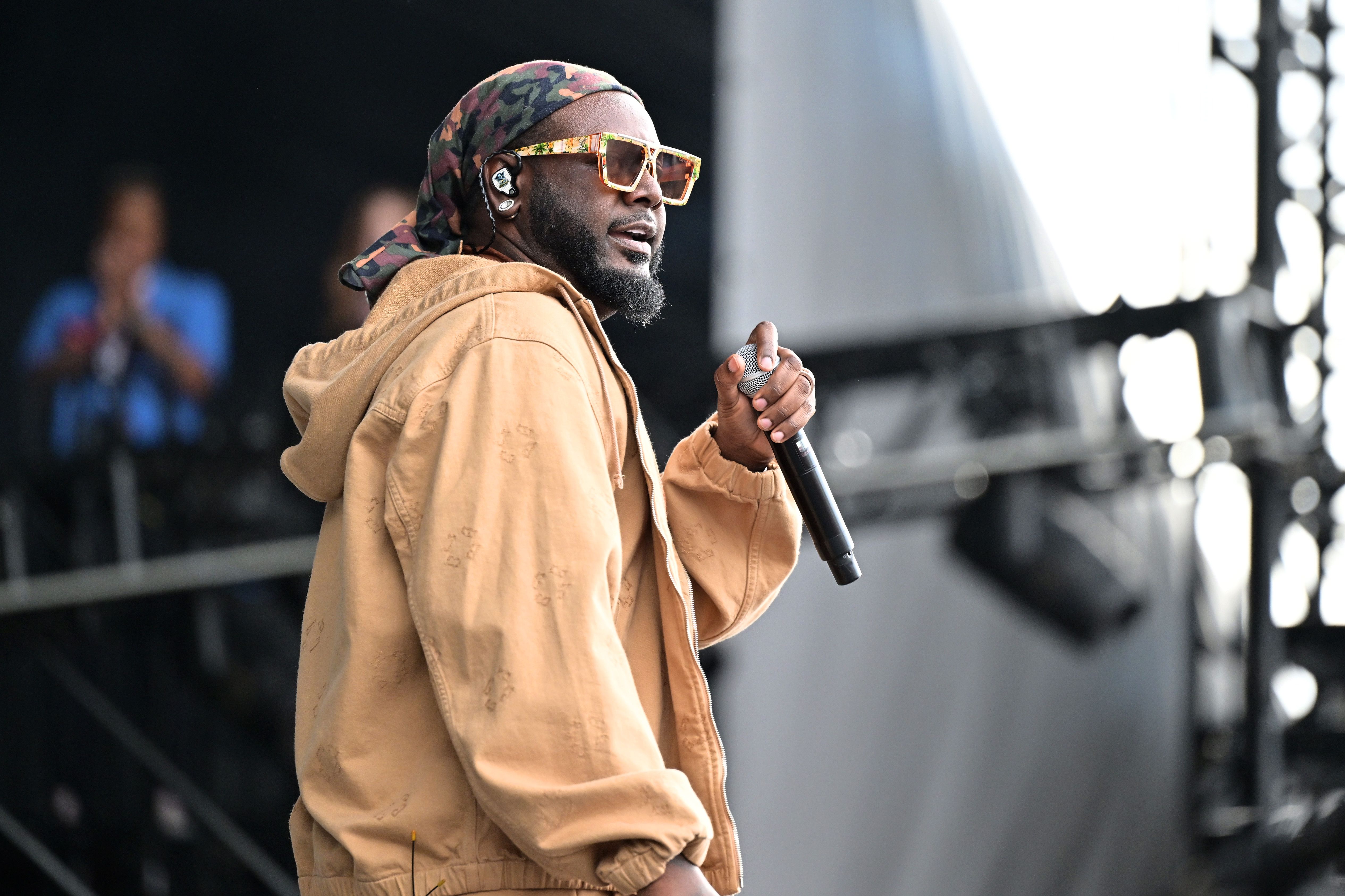 T-Pain performs onstage in a yellow jacket and sunglasses.
