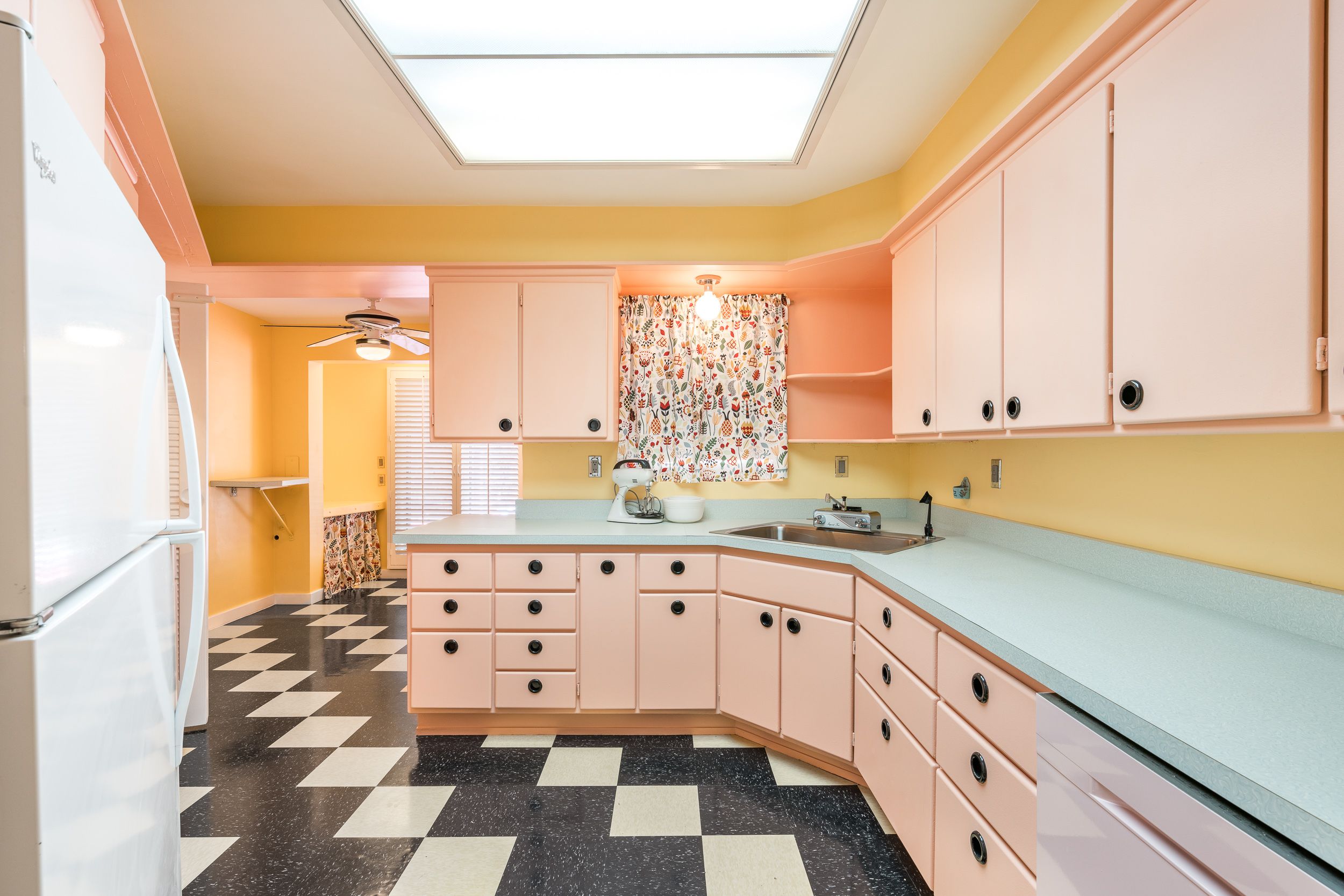 A pink and blue mid-century kitchen with checkered floors. 