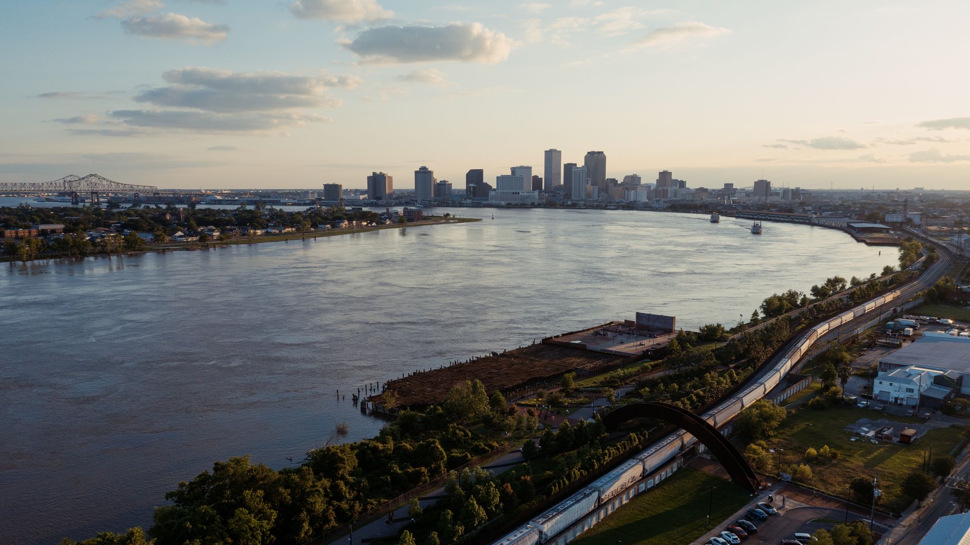 A view of the New Orleans skyline at sunset, viewed from the Bywater so downtown is at center, the curve of the river is next to it and the Crescent City Connection and Algiers Point are at left.