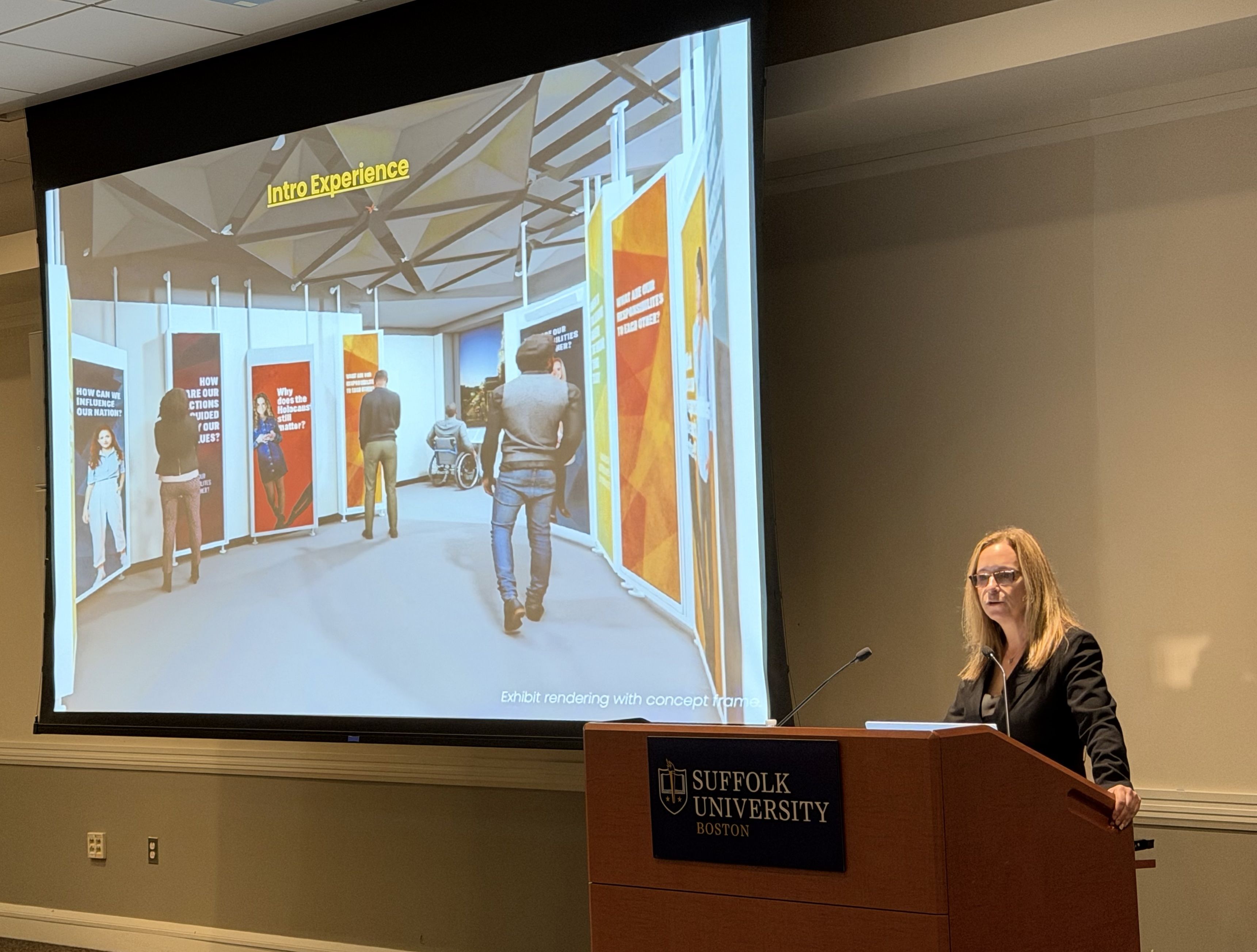 Jodi Kipnis, co-founder of the Holocaust Museum Boston, stands at a lectern and shares a glimpse of the museum with construction workers building the site at Suffolk University Law School next door.
