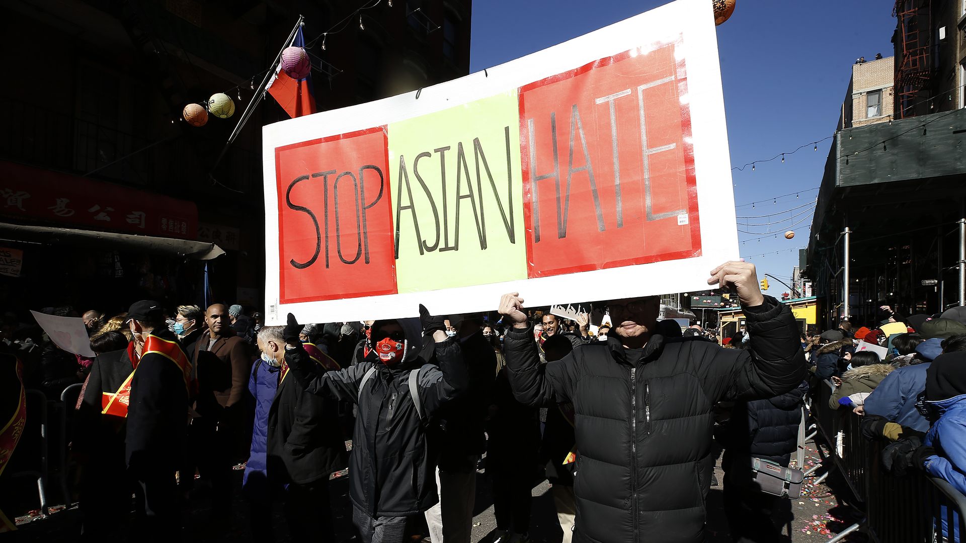 Photo of people holding a large red and yellow sign that says "Stop Asian Hate" in a parade in Chinatown