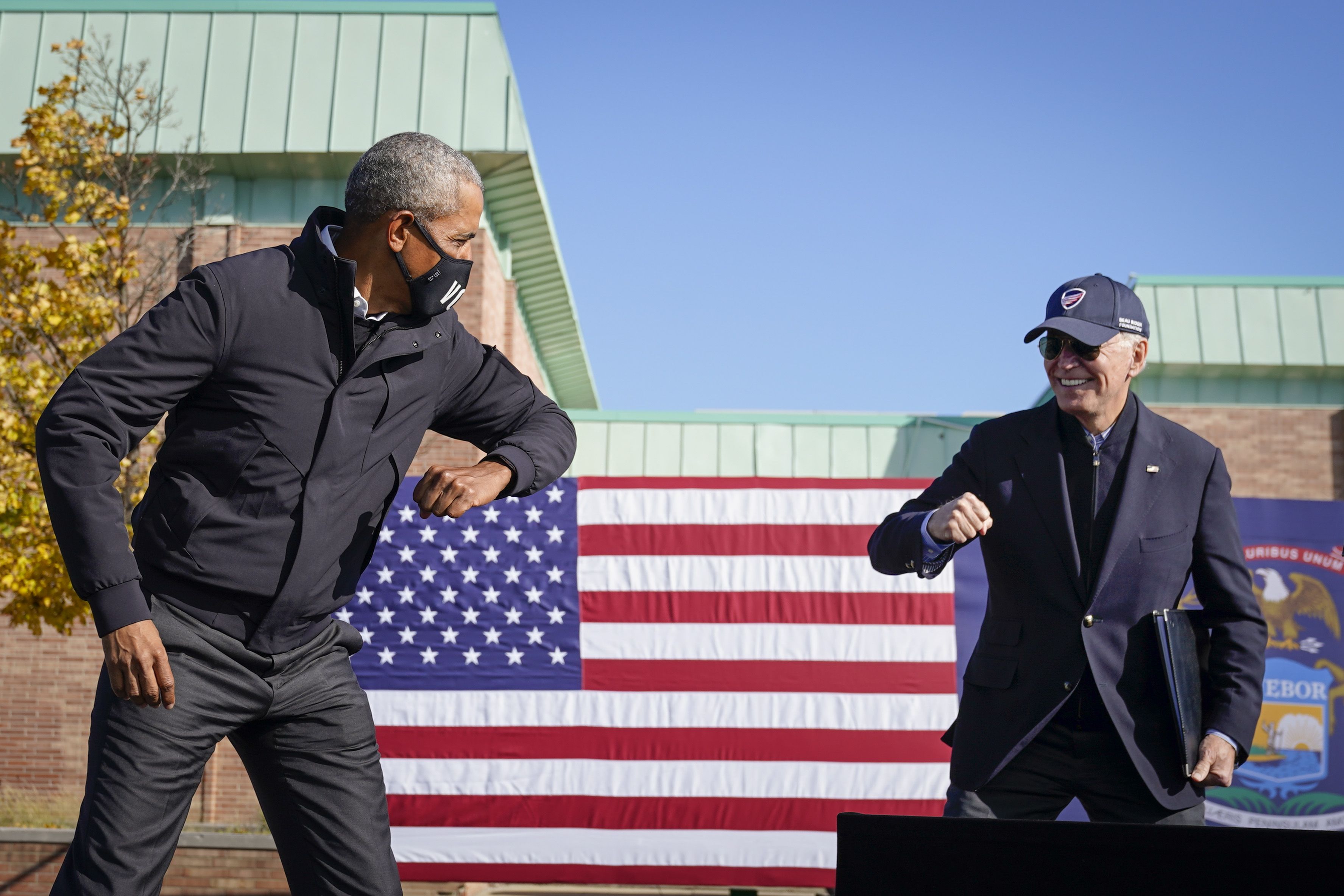 Former President Barack Obama and Joe Biden greet each other with a socially distant "air" elbow bump at Northwestern High School on October 31, 2020 in Flint, Michigan. 