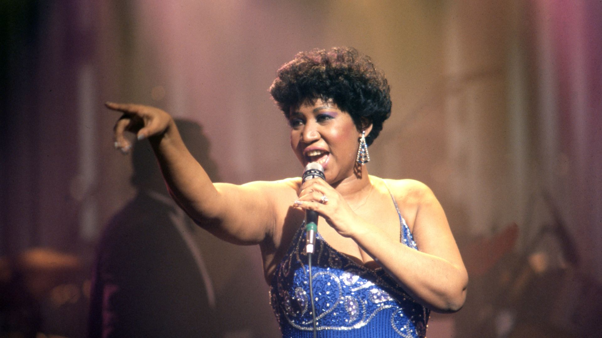 Aretha Franklin points to the crowd while singing on stage. 