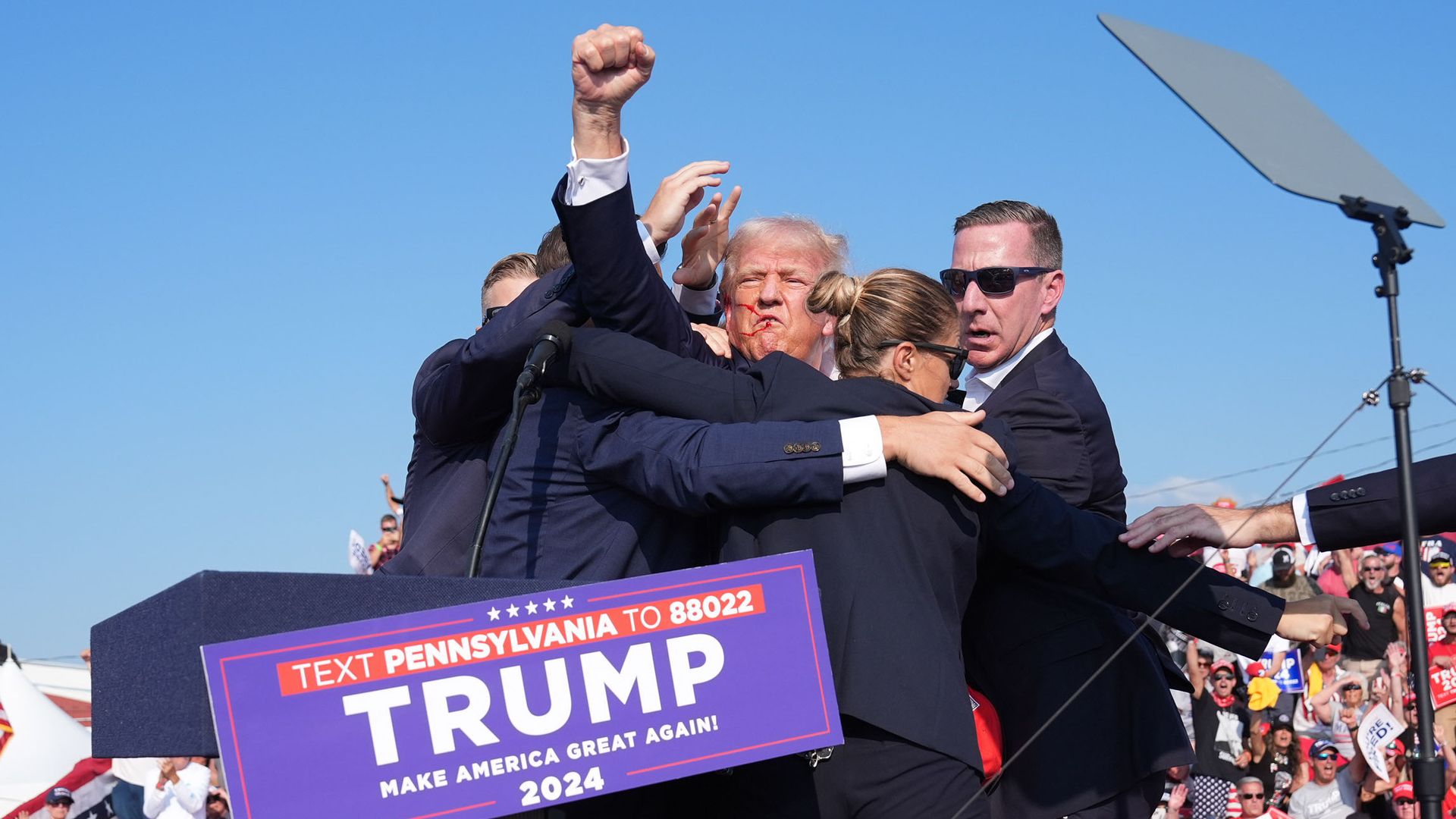 Donald Trump raises his arm with blood on his face after being shot at during a campaign rally at Butler Farm Show Inc. on Saturday, July 13, 2024 in Butler, Pa. 