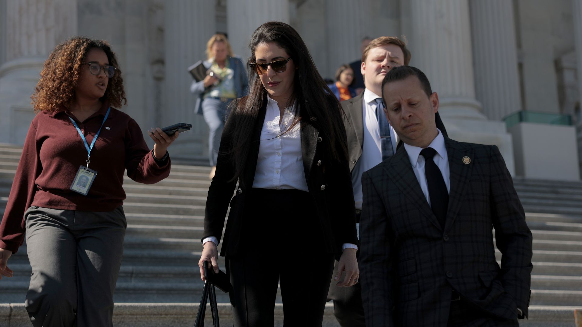 Anna Paulina Luna, flanked by Jared Moskowitz and a reporter, wearing a black jacket and white shirt and walking down the Capitol steps.