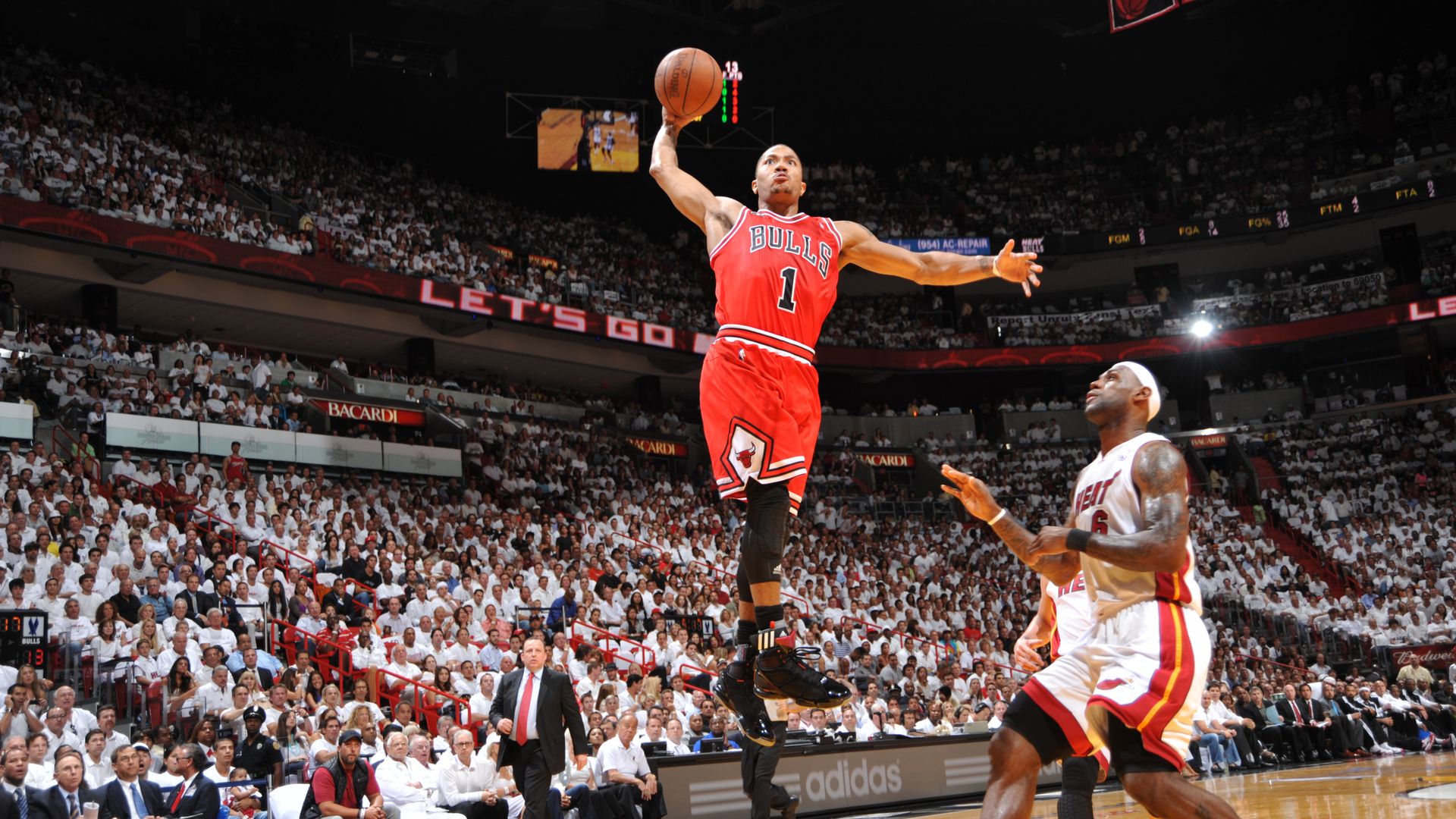 Basketball game with a Chicago Bulls player in red jersey #1 jumping for a shot over two Miami Heat players in white jerseys, with a packed crowd in the arena.