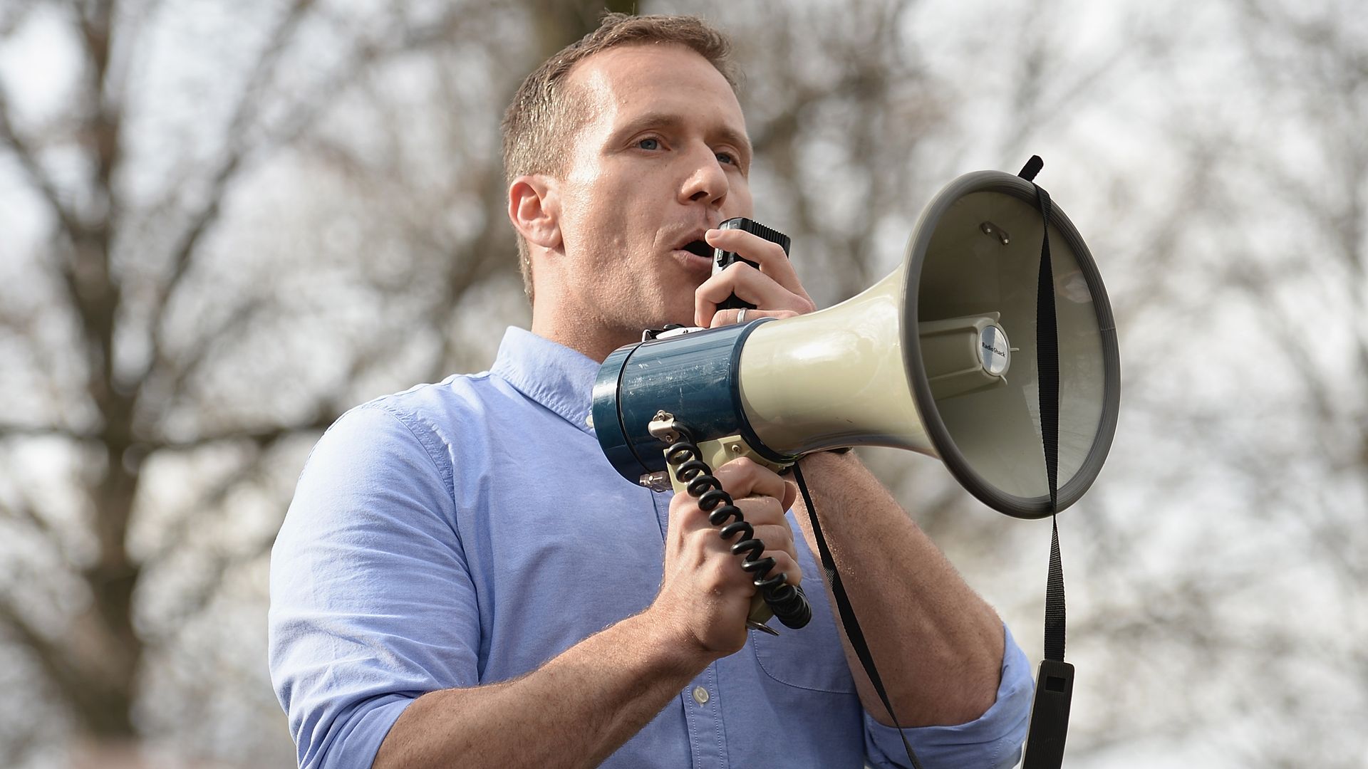Eric Greitens speaks into a megaphone while standing outside