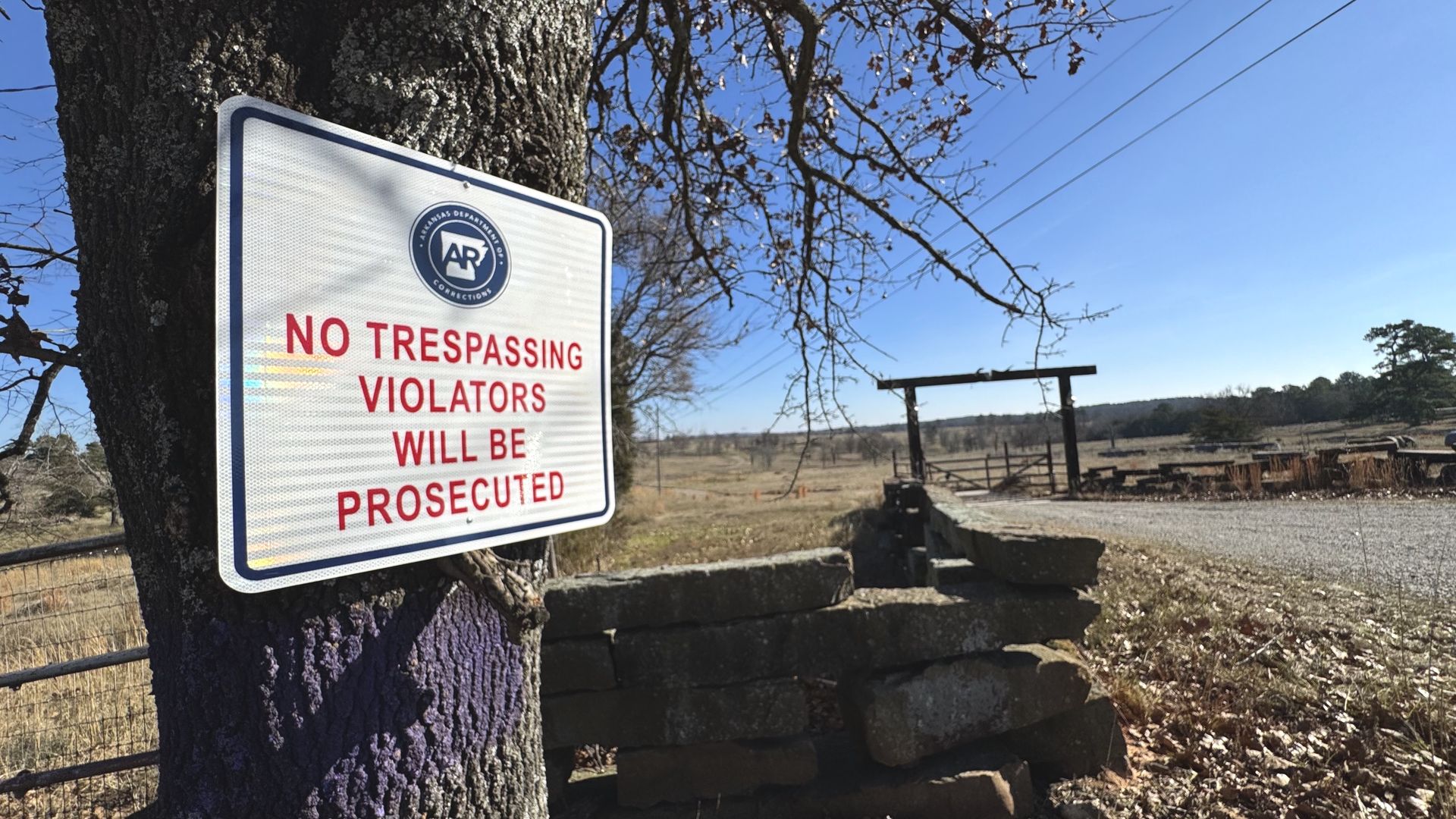 Photo of a no trespassing sign by the State of Arkansas with farmland in the background.