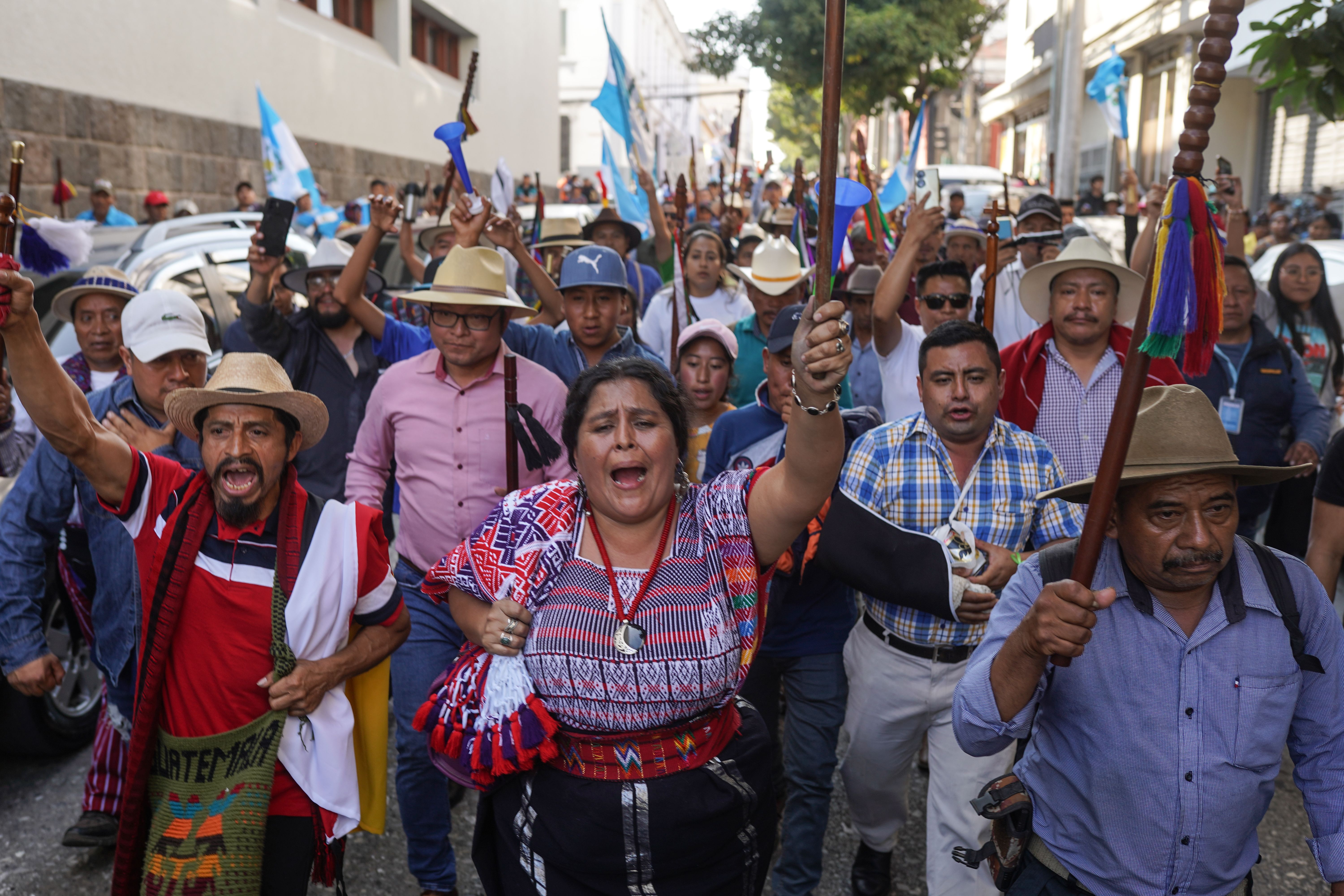 Several people march in a street protesting in Guatemala City during the delays of new President Bernardo Arévalo's inauguration