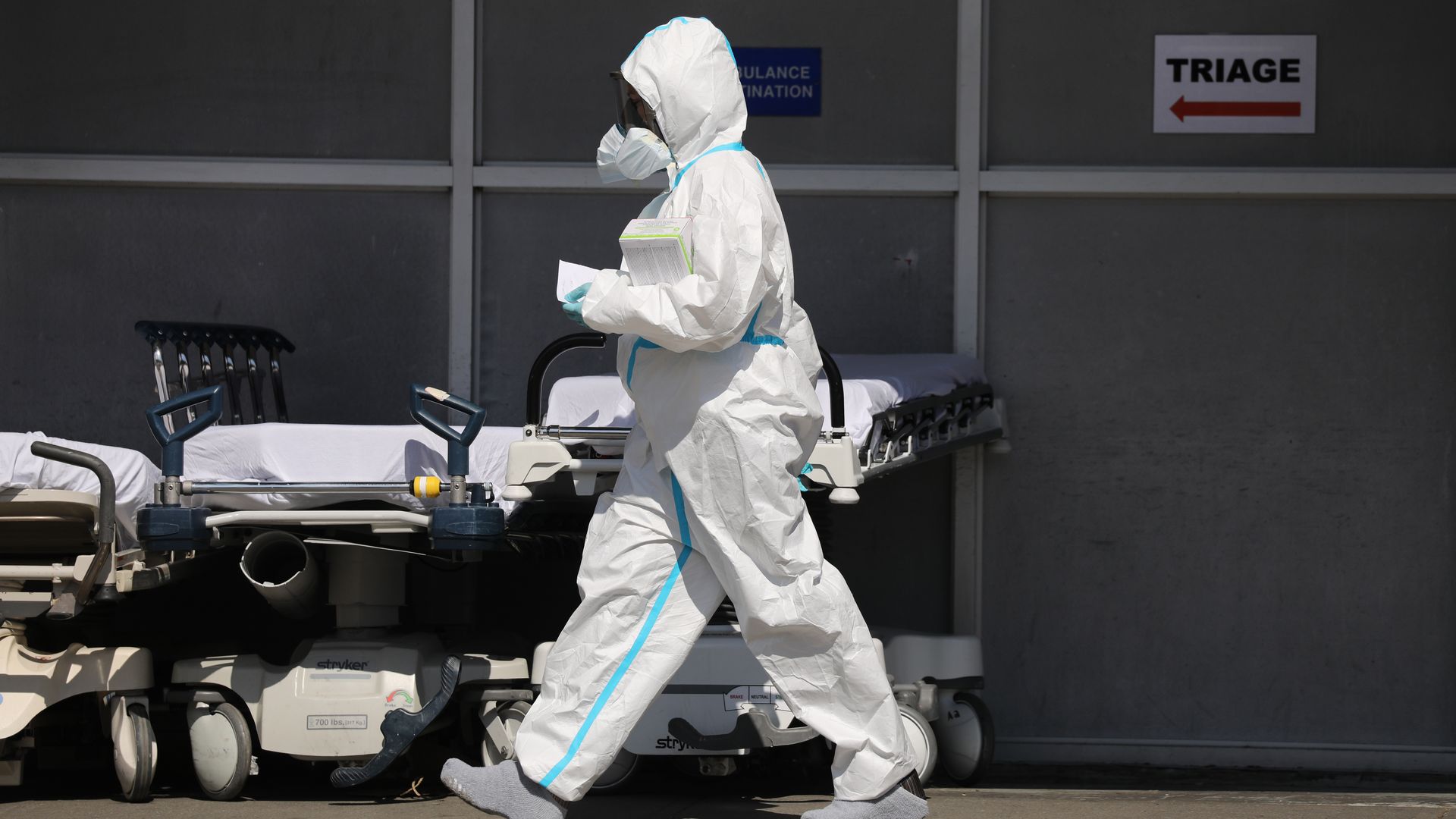 In this image, a person in personal protective gear walks