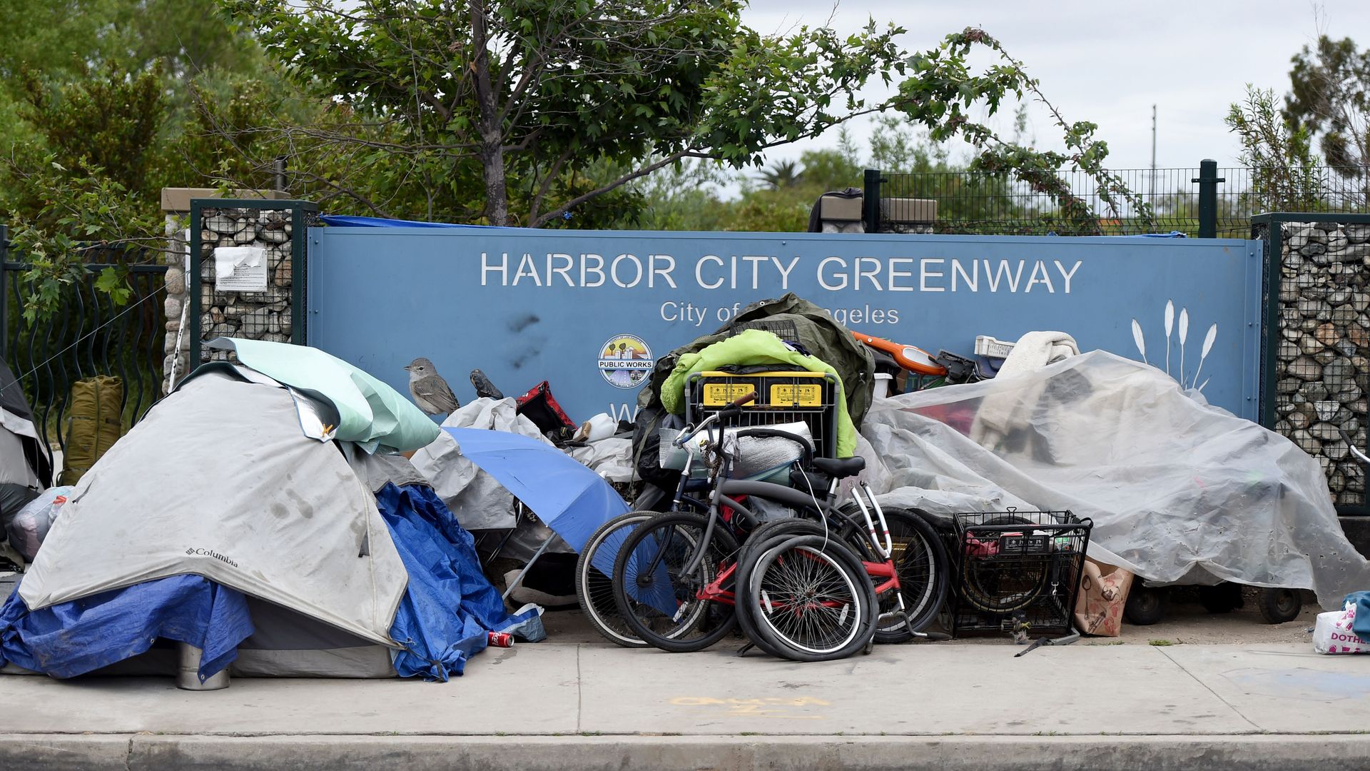 homeless people sleeping in front of a suburb sign in los angeles