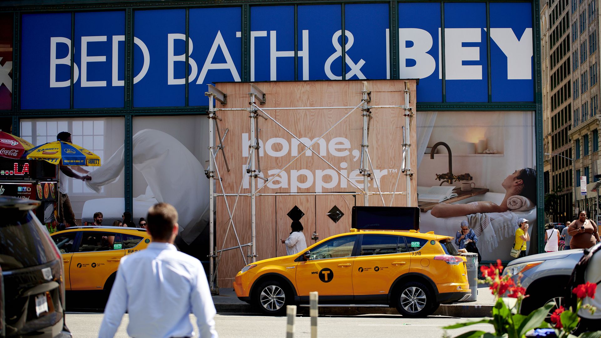 A Bed Bath & Beyond store located on a city street is undergoing renovations, with the exterior covered in scaffolding.