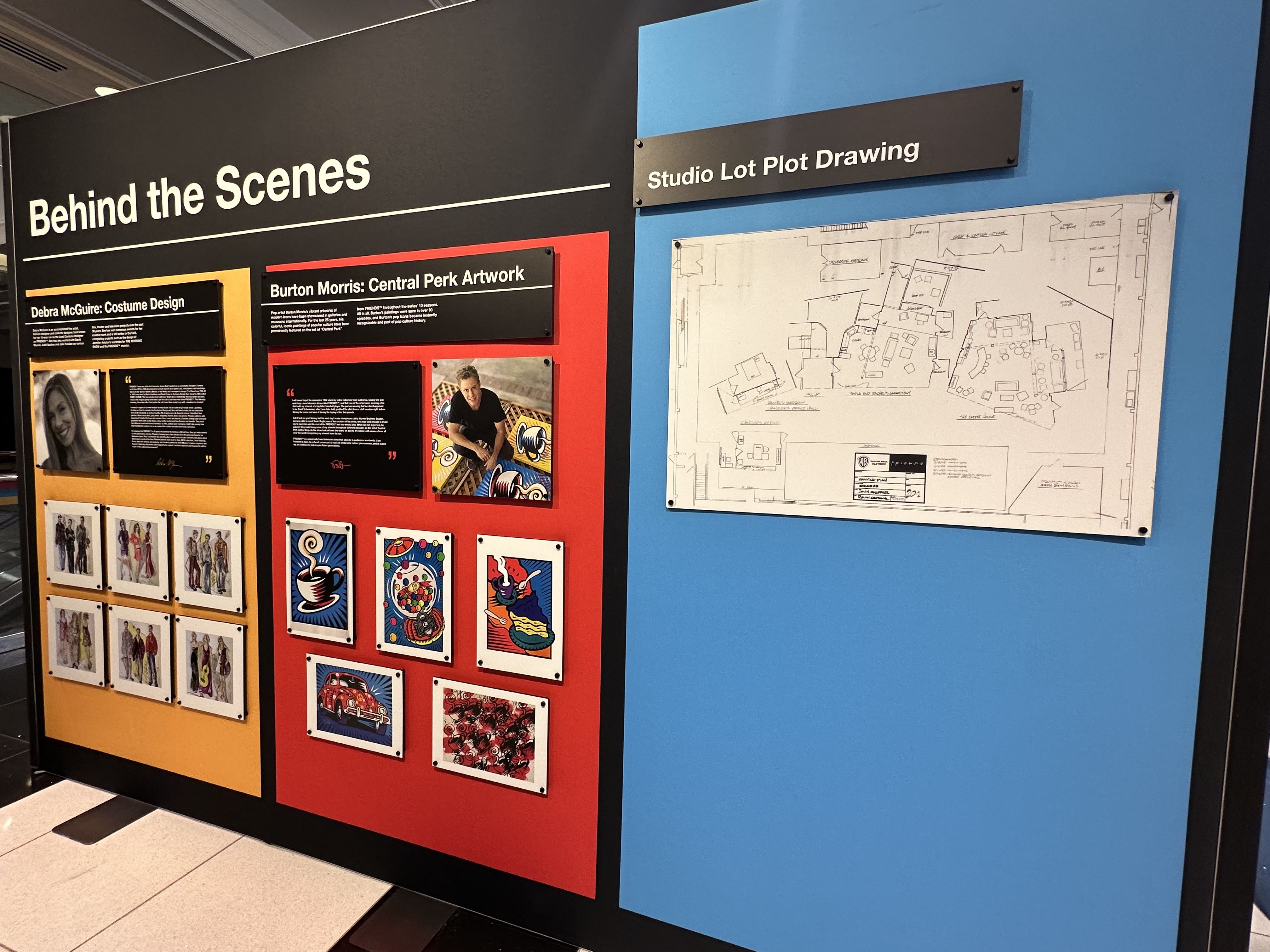 A photo of an installation at "The Friends Experience" in Boston showing a studio plot drawing, art from artist Burton Morris, which appeared in Central Perk, and costume designs by designer Debra McGuire.