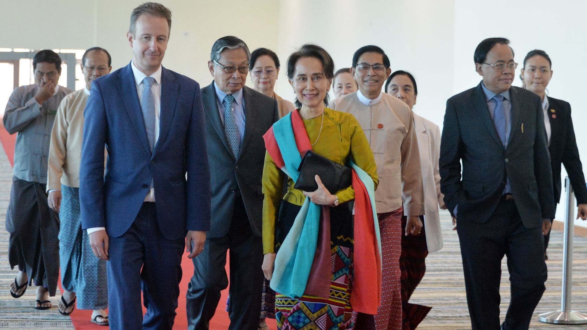 Aung San Suu Kyi, flanked by officials, leaving the nation's capital, Naypyidaw