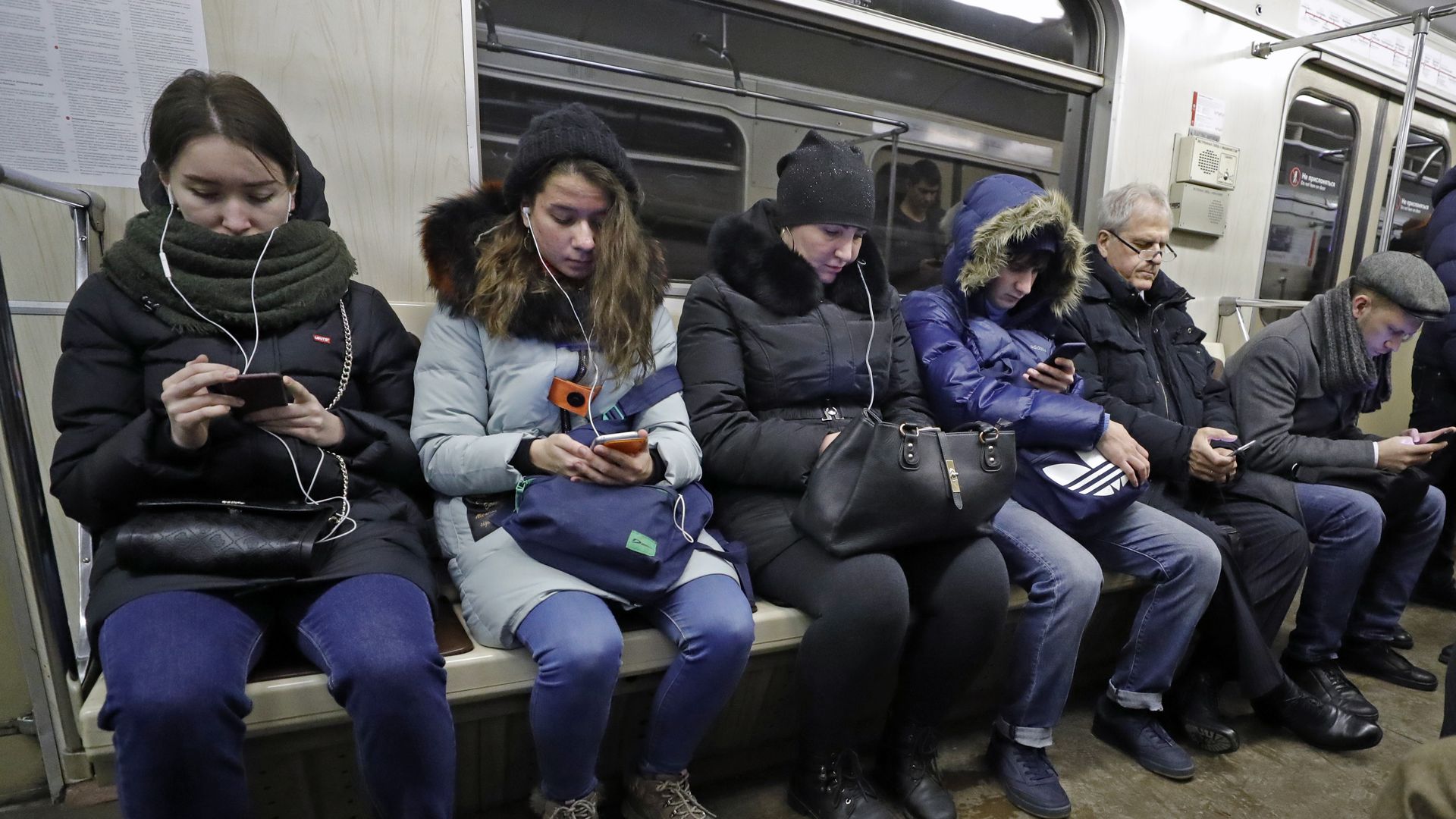 Photo of people looking at their phones on a subway