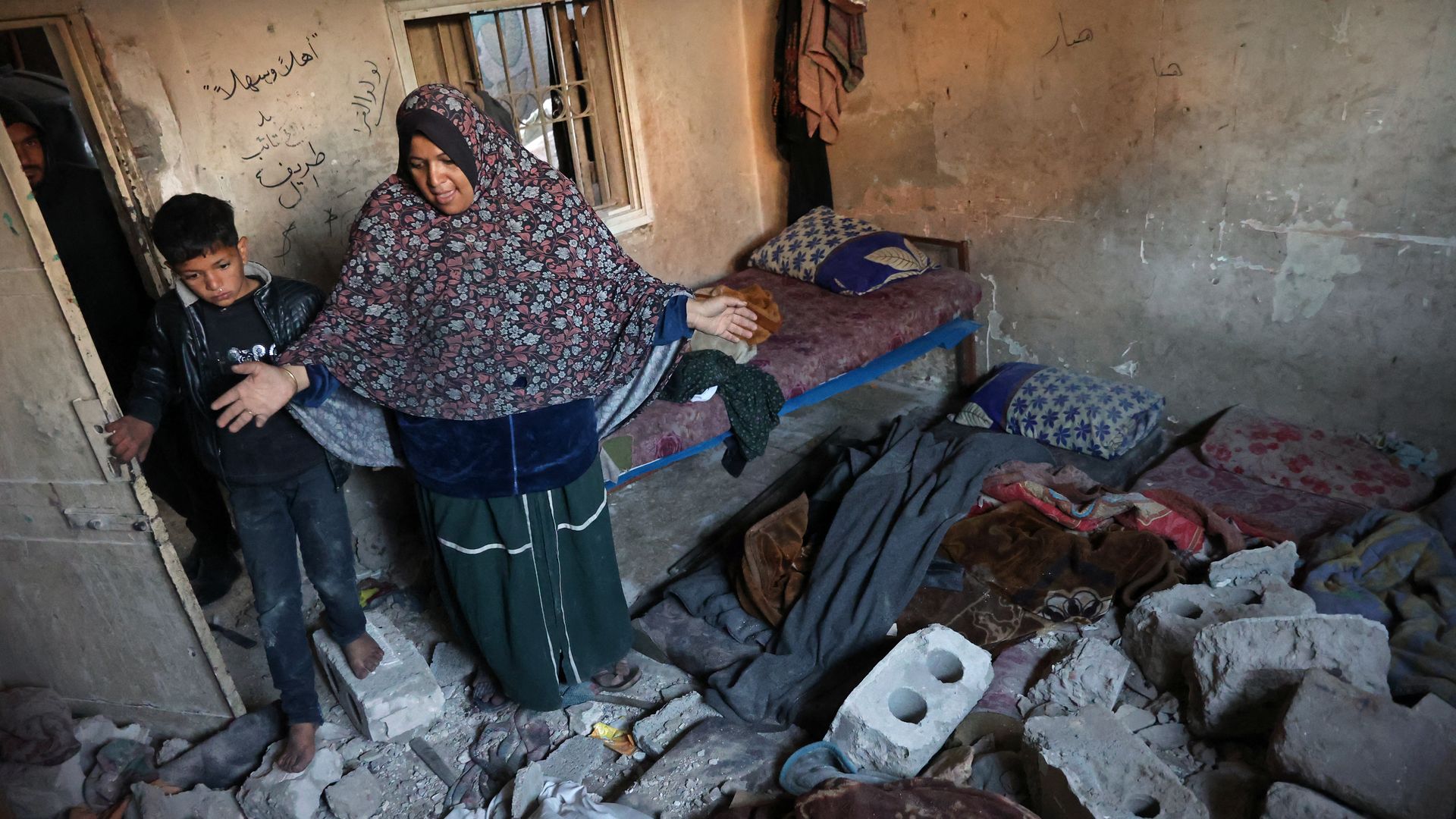 A woman reacts next to the rubble of a school, housing displaced Palestinians, which was destroyed in an Israeli strike in Gaza City on January 13, 2025,