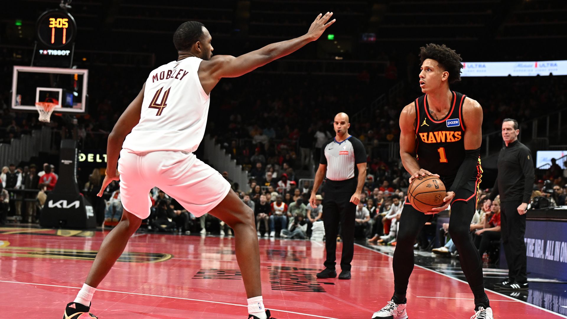 Basketball players in white and black on red court. One player holds ball wearing black hawks jersey. Defender in white, No. 4. 