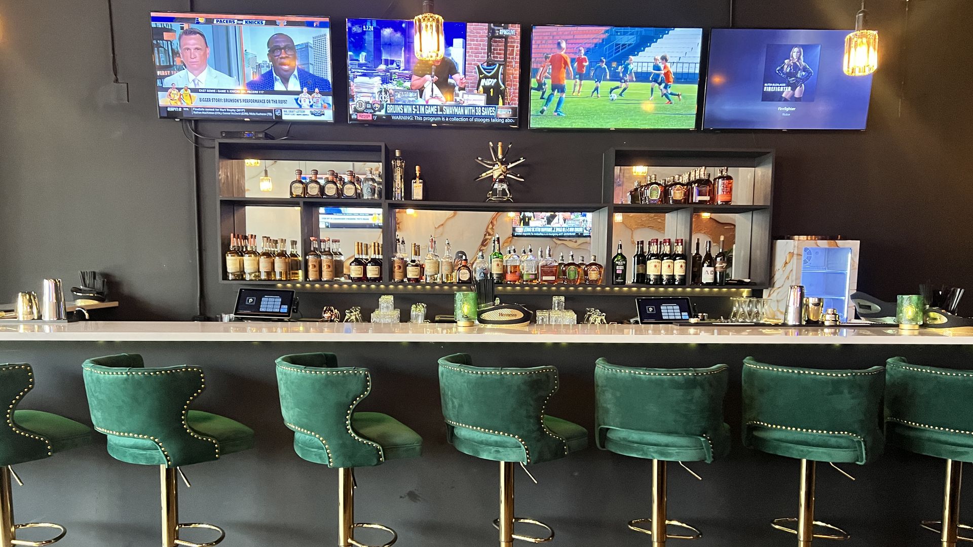 bar with tv screens on the far wall and several stool seats 