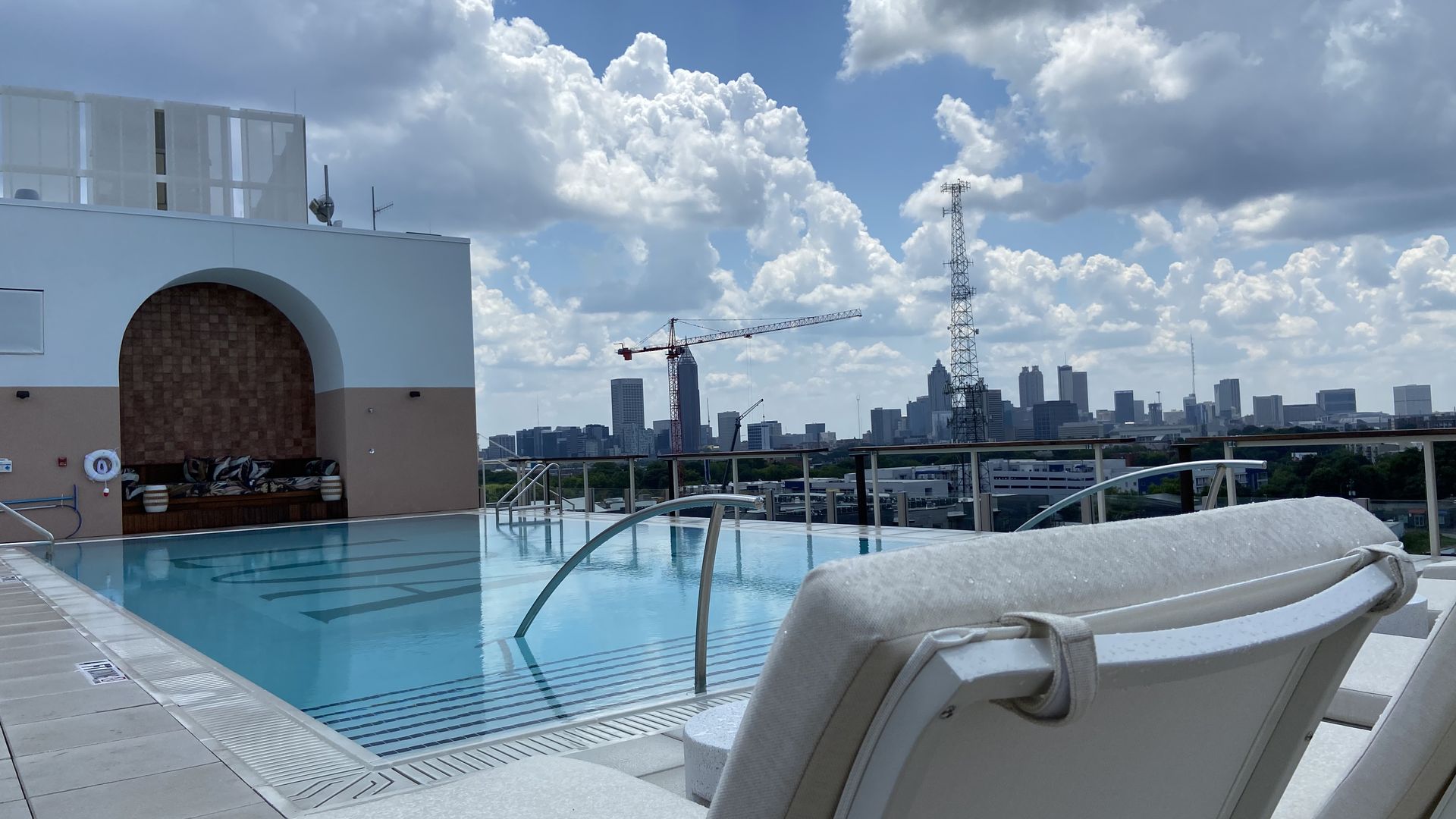 A rooftop pool and grotto on a sunny day with the Atlanta skyline in the background. 