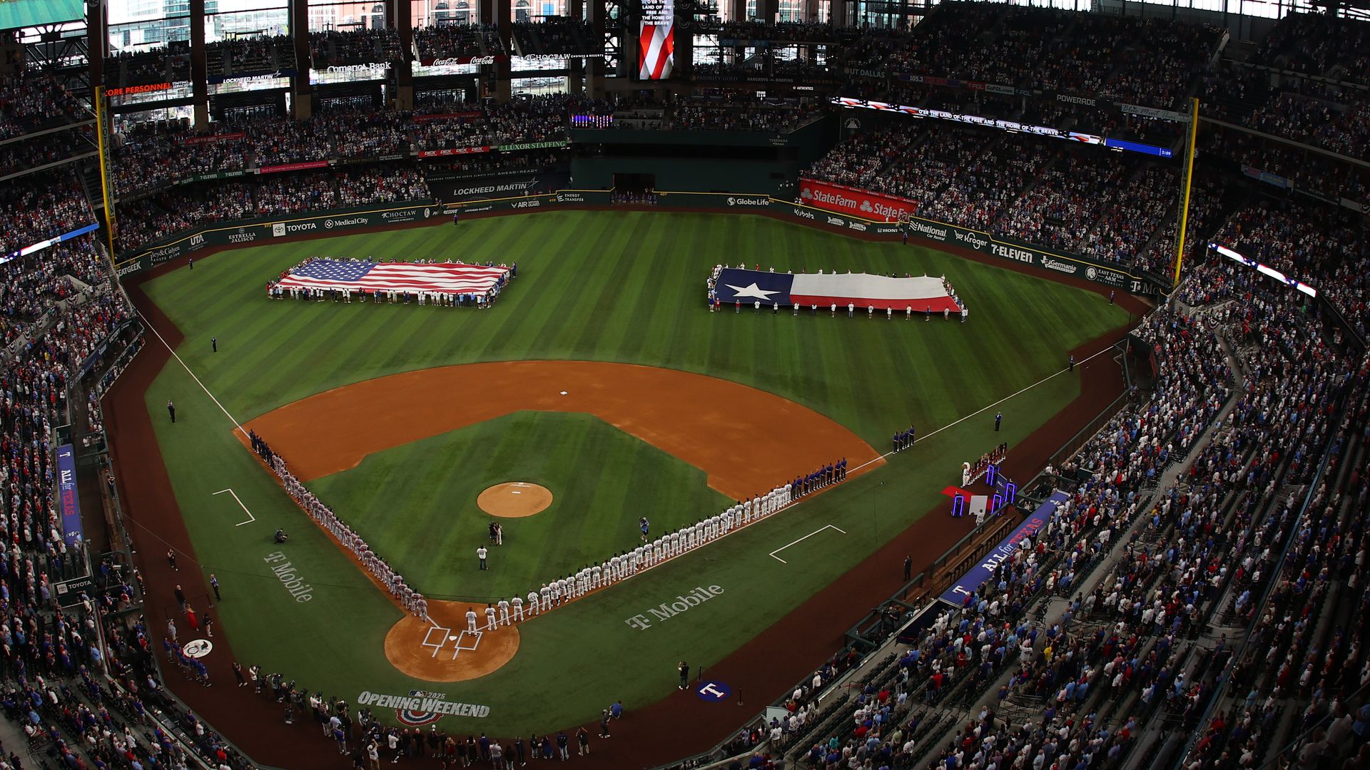 The Boston Red Sox and the Texas Rangers stand for the National Anthem at Globe Life Field .
