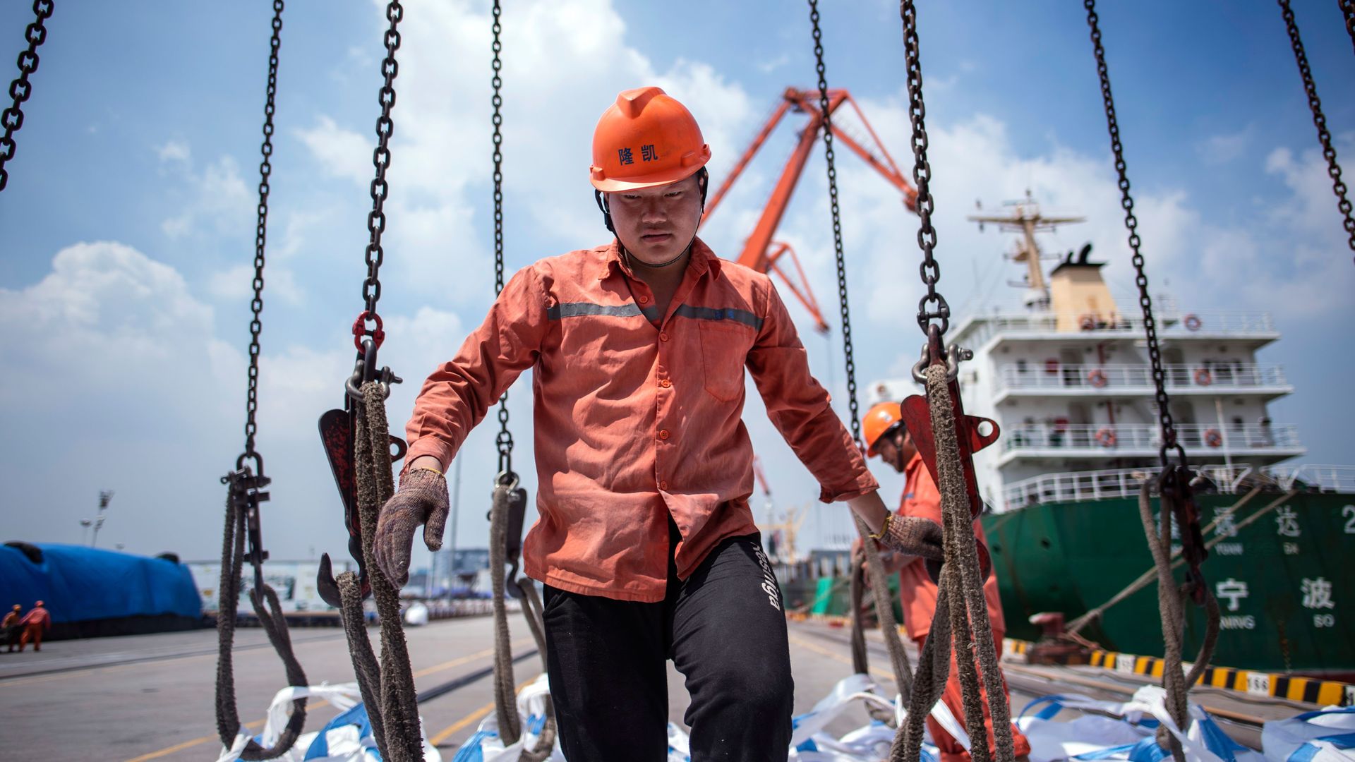 Chinese worker unloading bags of chemicals at a port