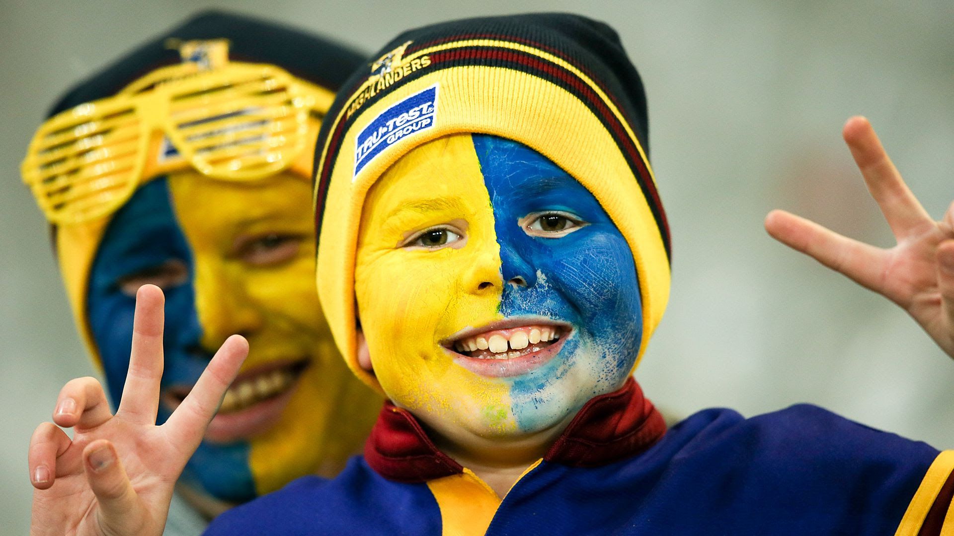 A young rugby fan has his face painted blue and yellow to support the Highlanders in New Zealand