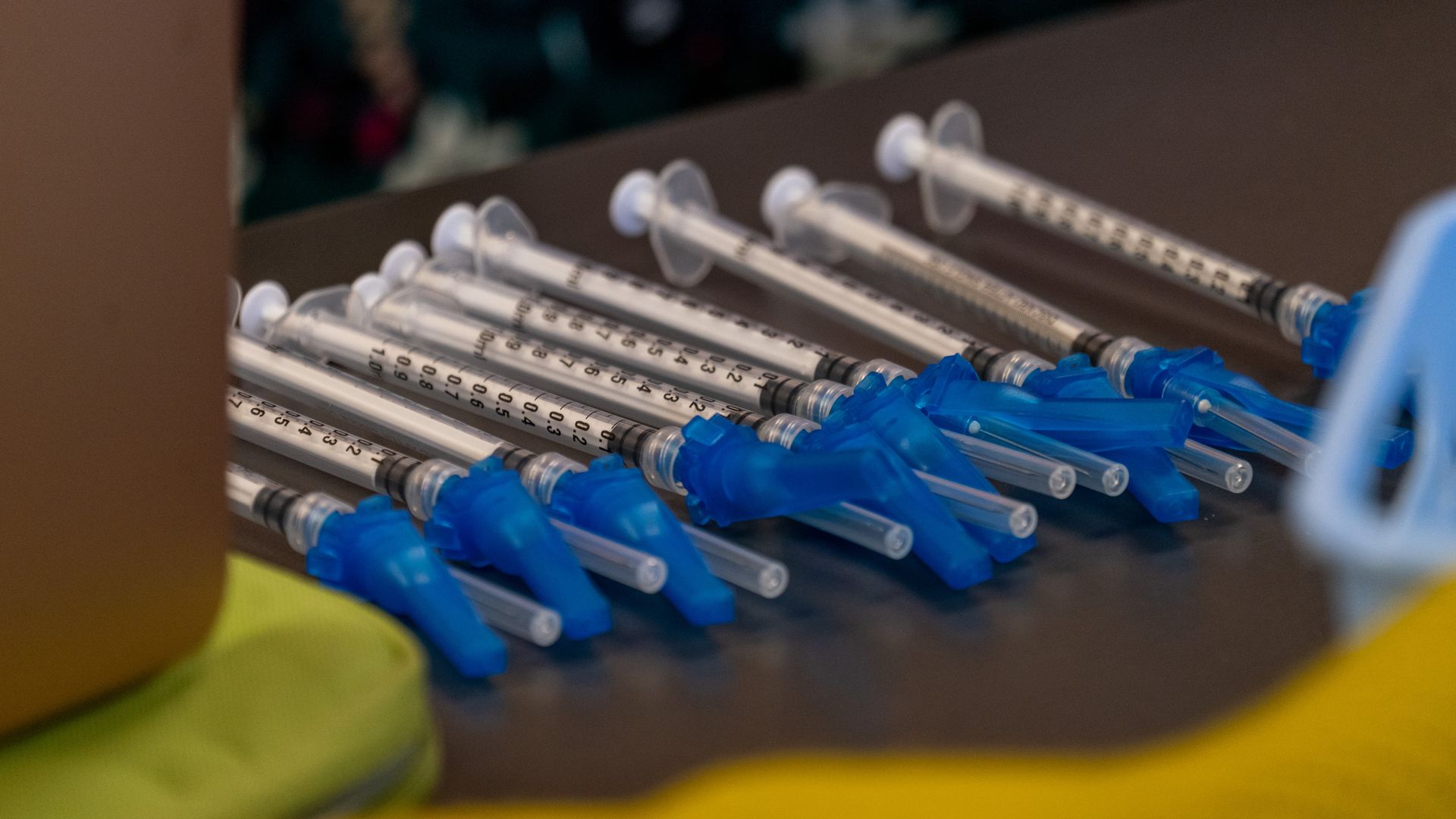 Several syringes lay side by side on a wooden table