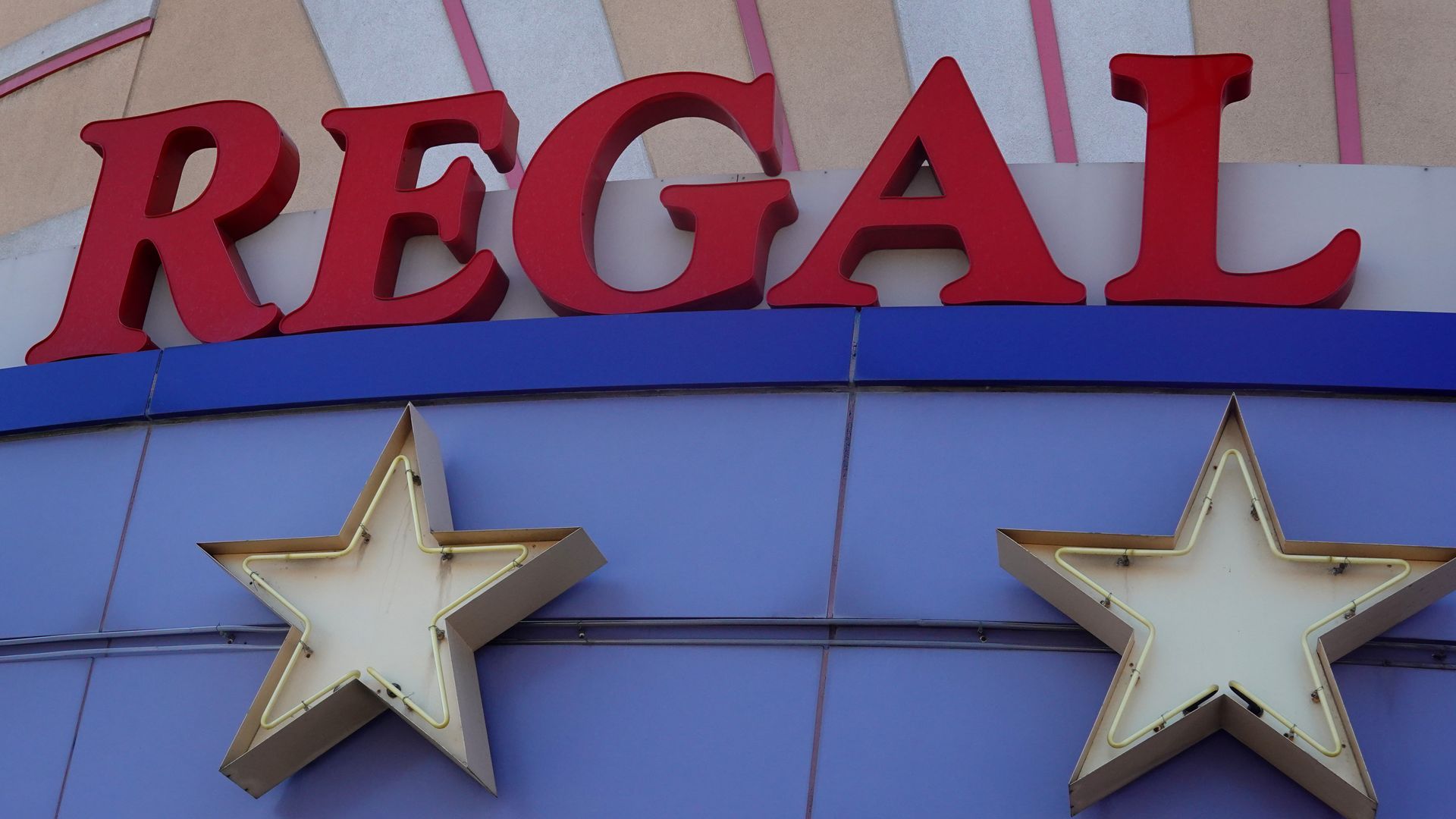 Sign says Regal with stars underneath on exterior of movie theater building