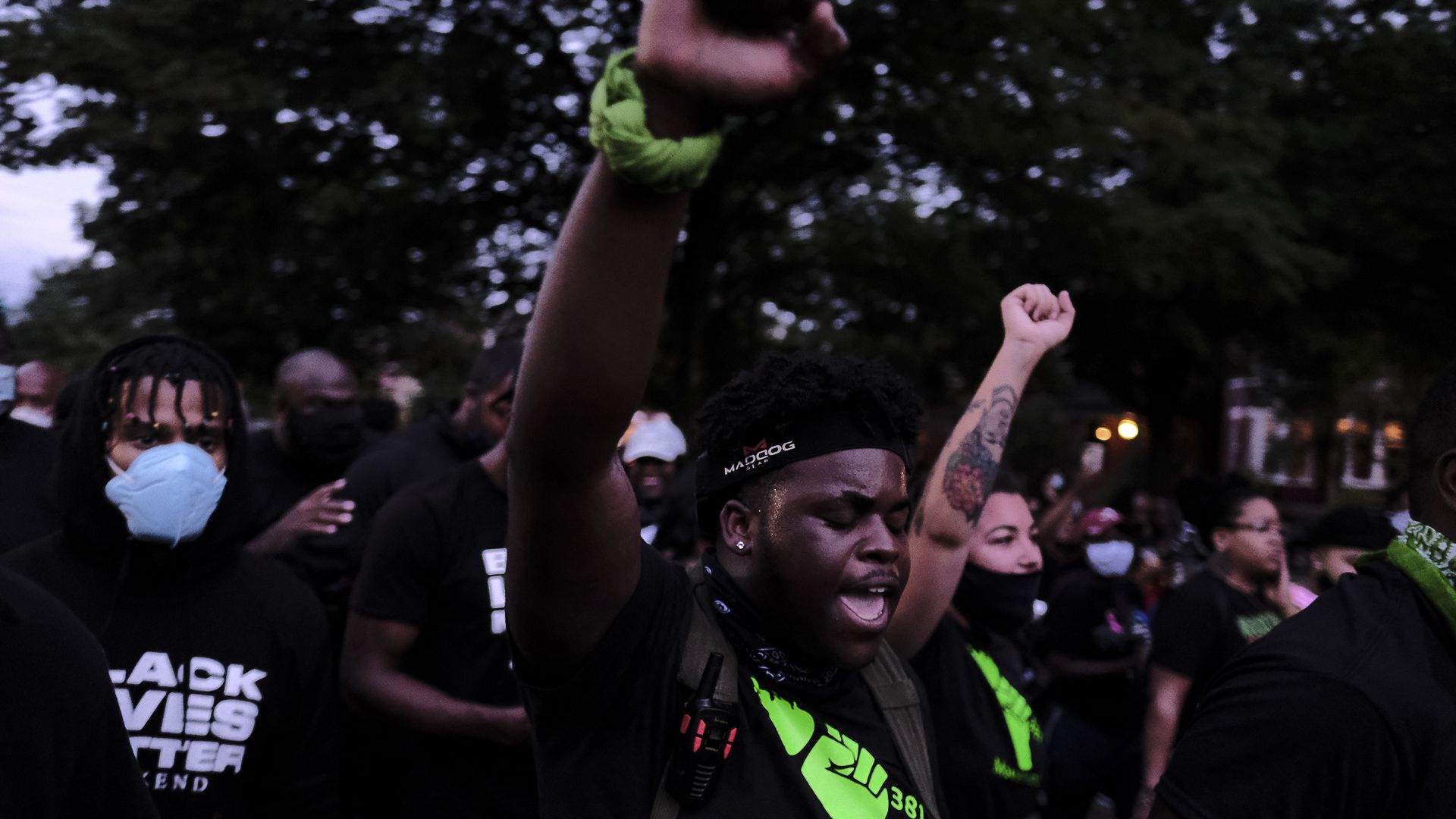 A man with raised fist marches in the street. 