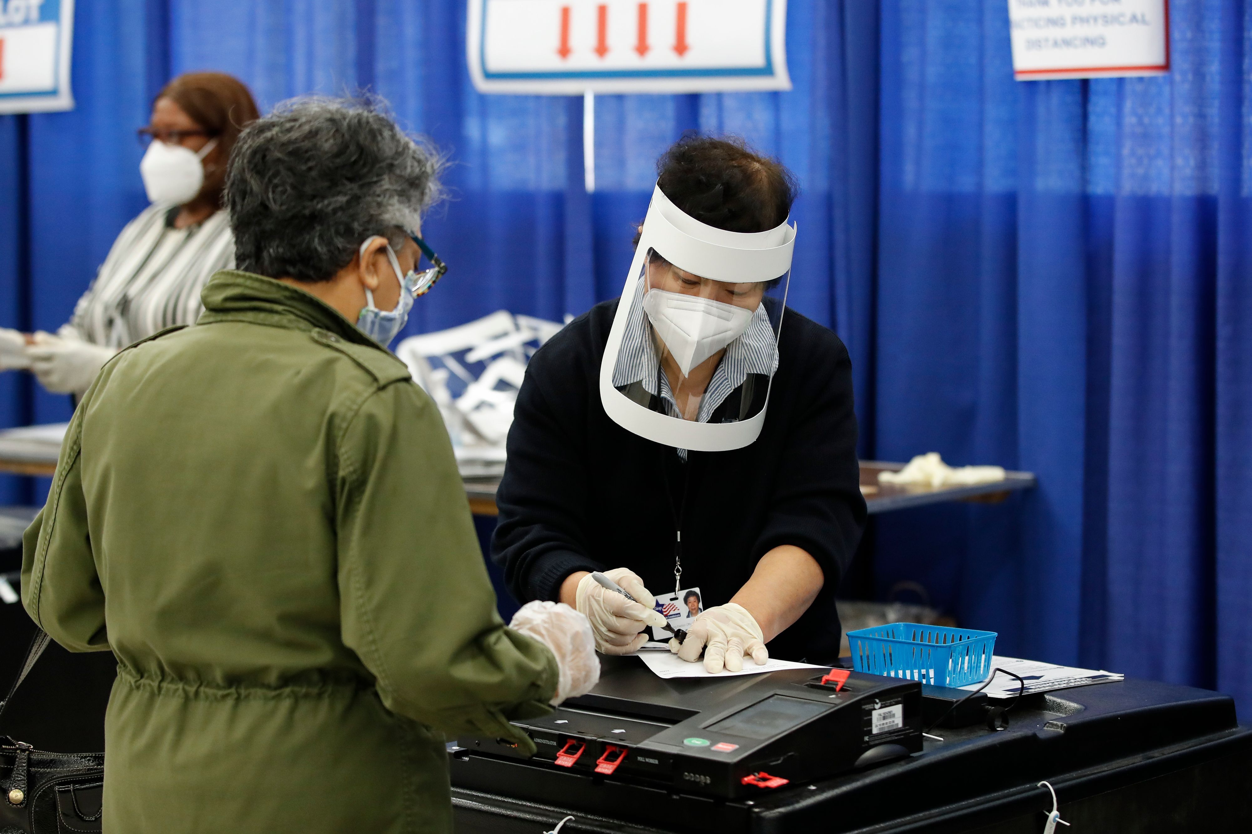 Photo of woman voting with election judge wearing mask