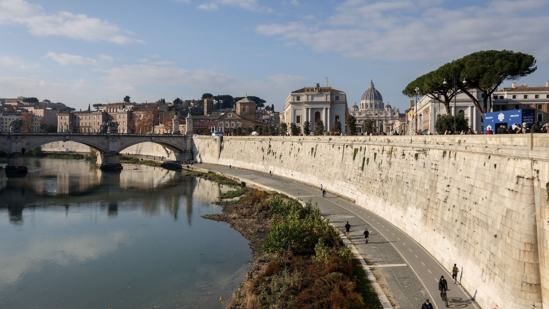 A view of the River Tiber with a bridge crossing and a mixture of ancient. medieval and baroque buildings. 