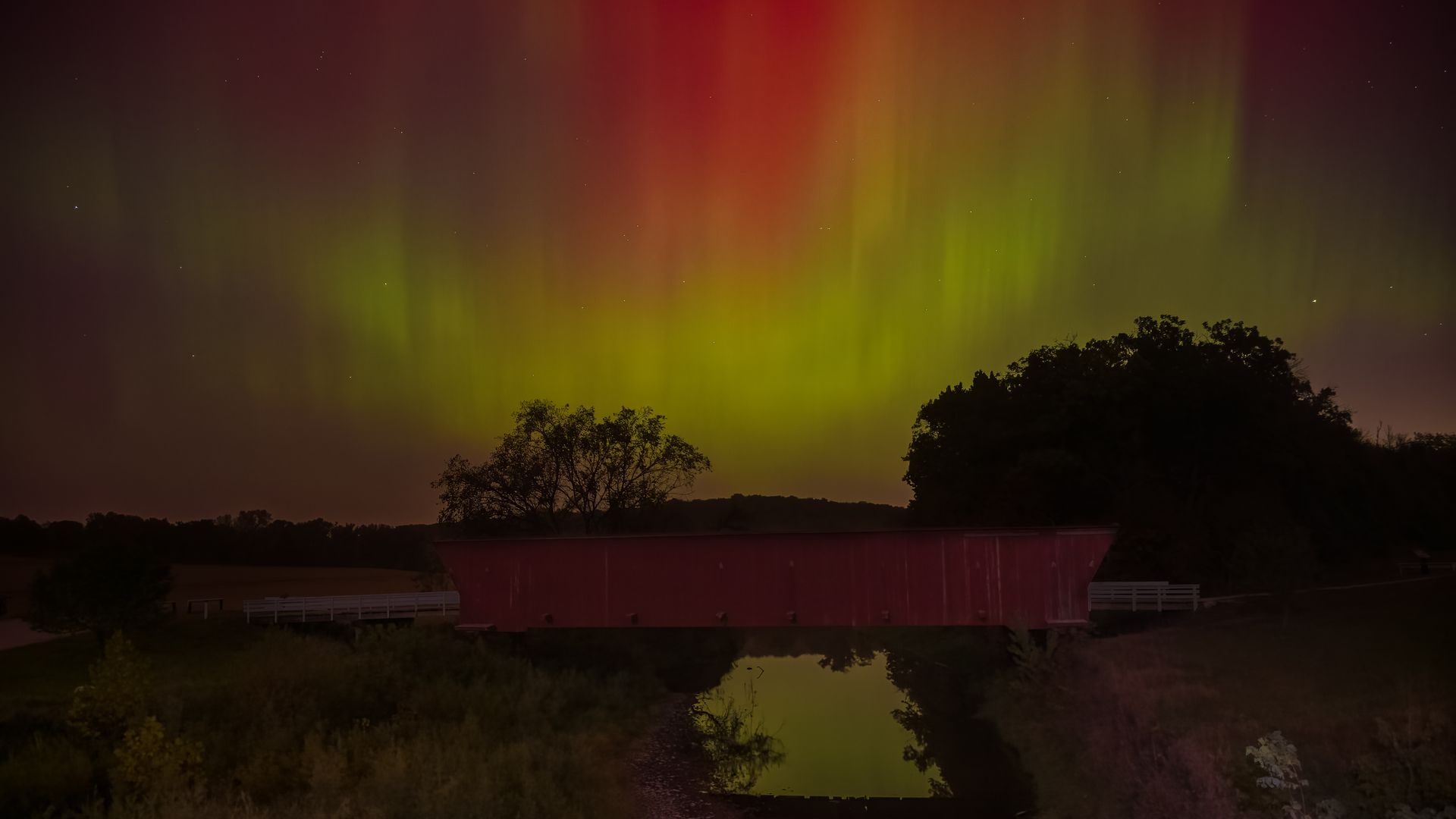 The Northern Lights showing vividly over a covered bridge