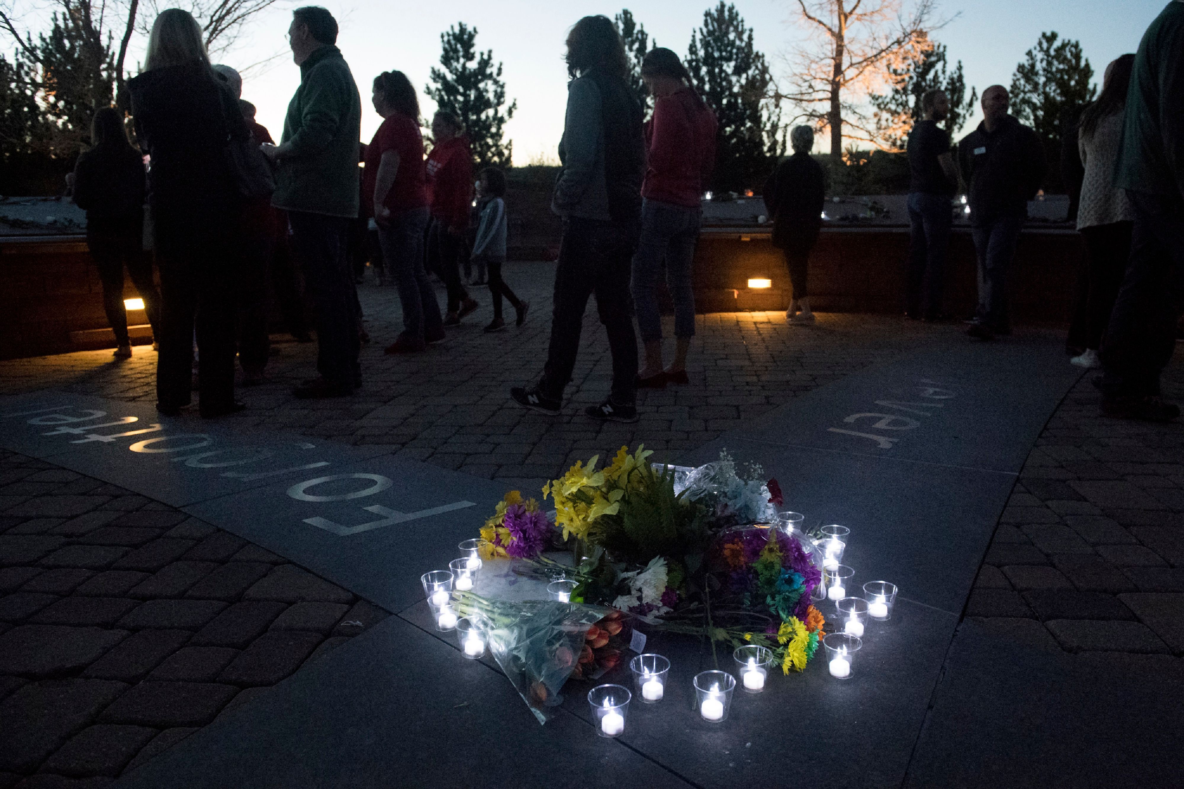 Candles wrap around a collection of flowers at the Columbine Memorial at Clement Park in Littleton, Colorado, during a community vigil.