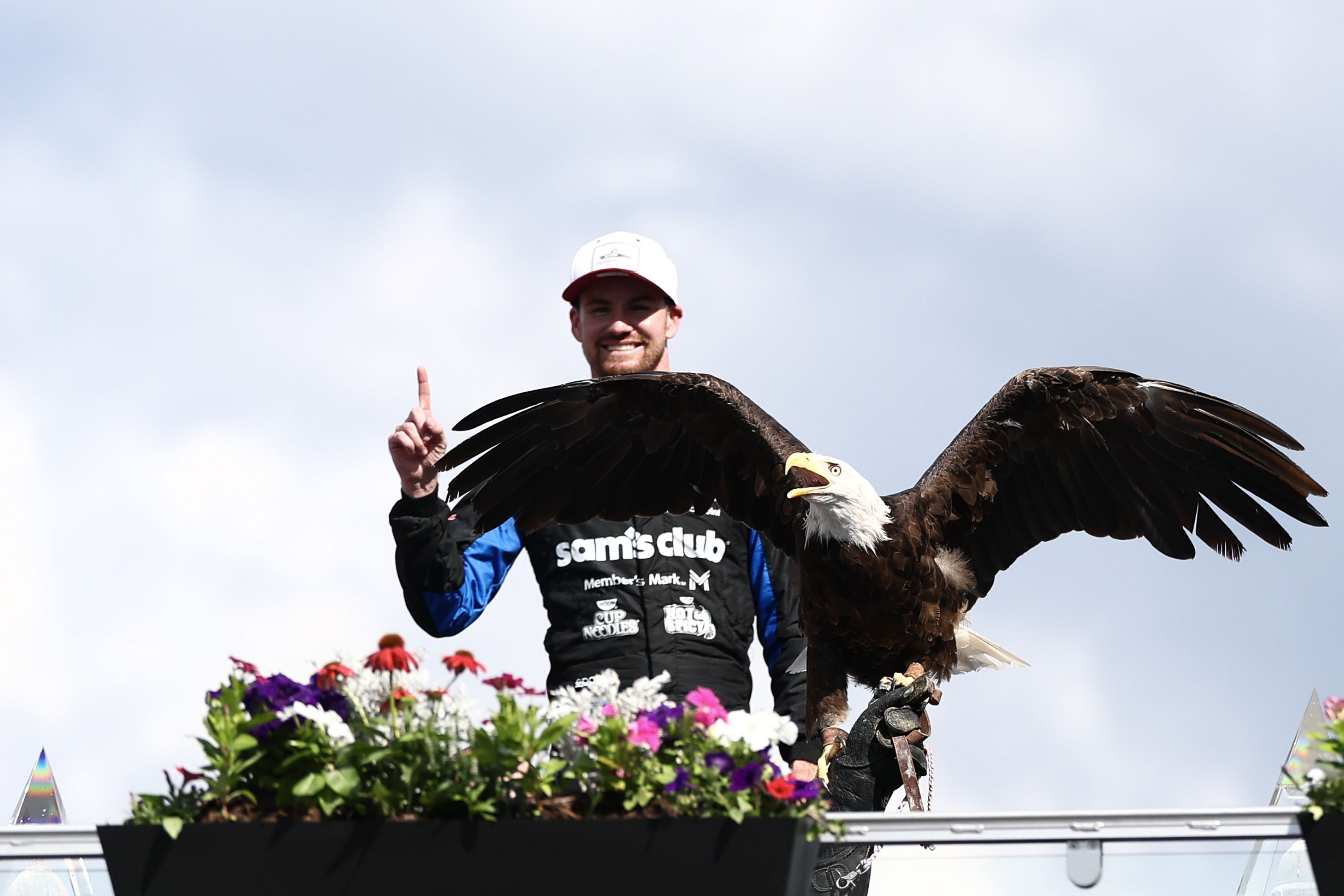 Kyle Kirkwood poses holding up a No. 1 with his finger, behind a live bald eagle.