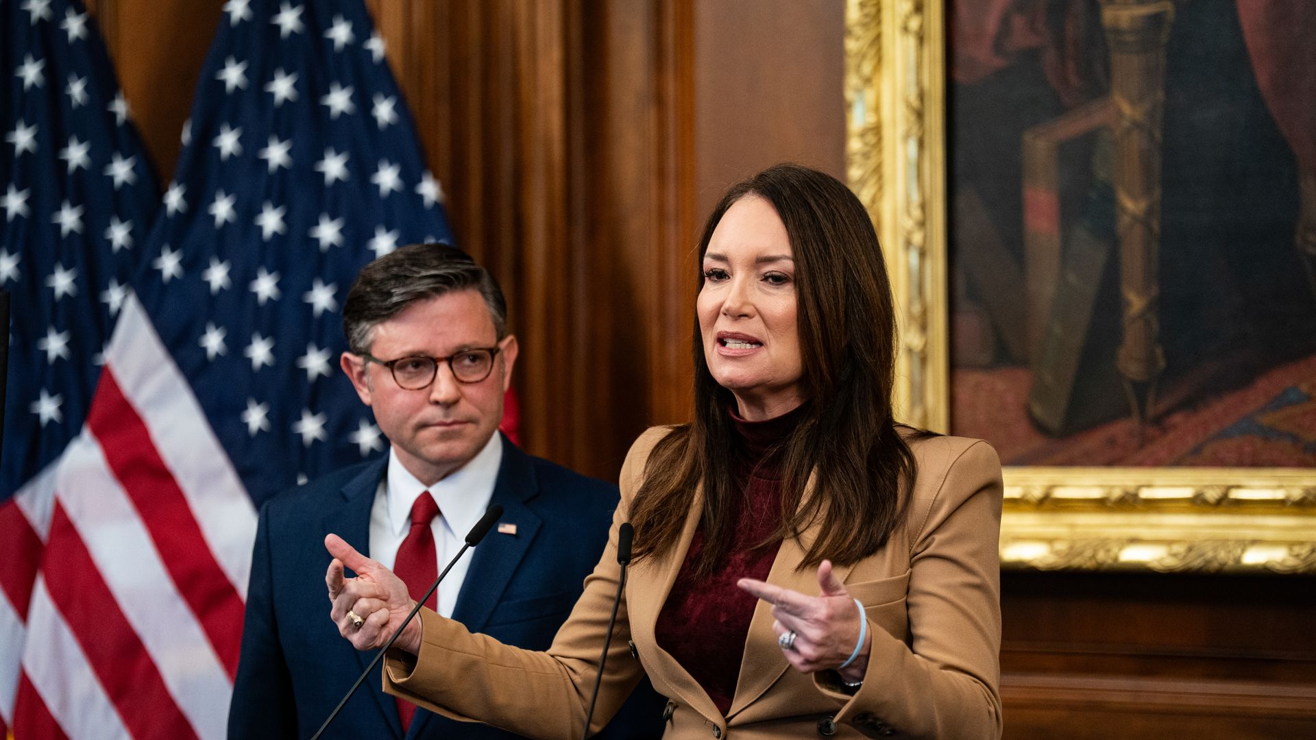 Rollins wearing a tan blazer and red shirt and Johnson wearing a blue suit jacket, white shirt and red tie 
