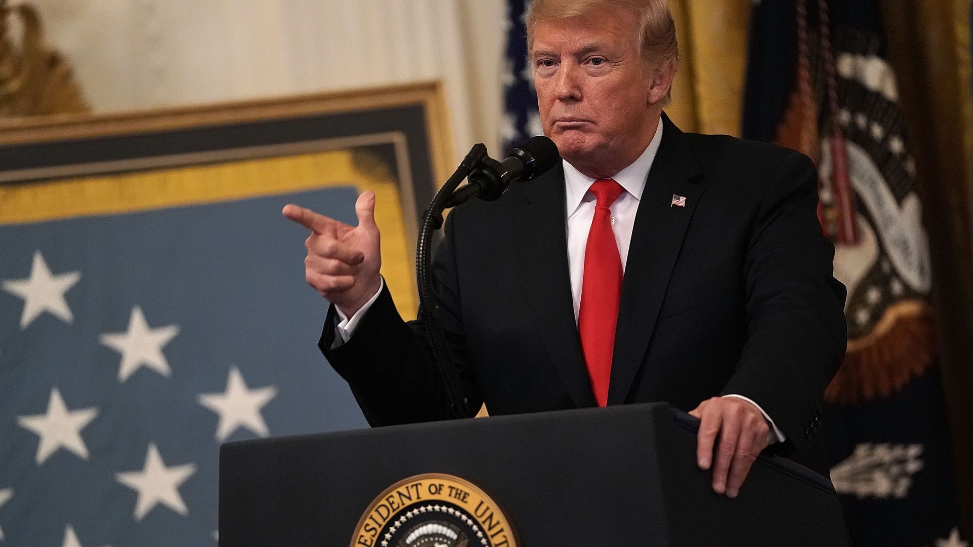 Donald Trump standing at the podium, pointing.