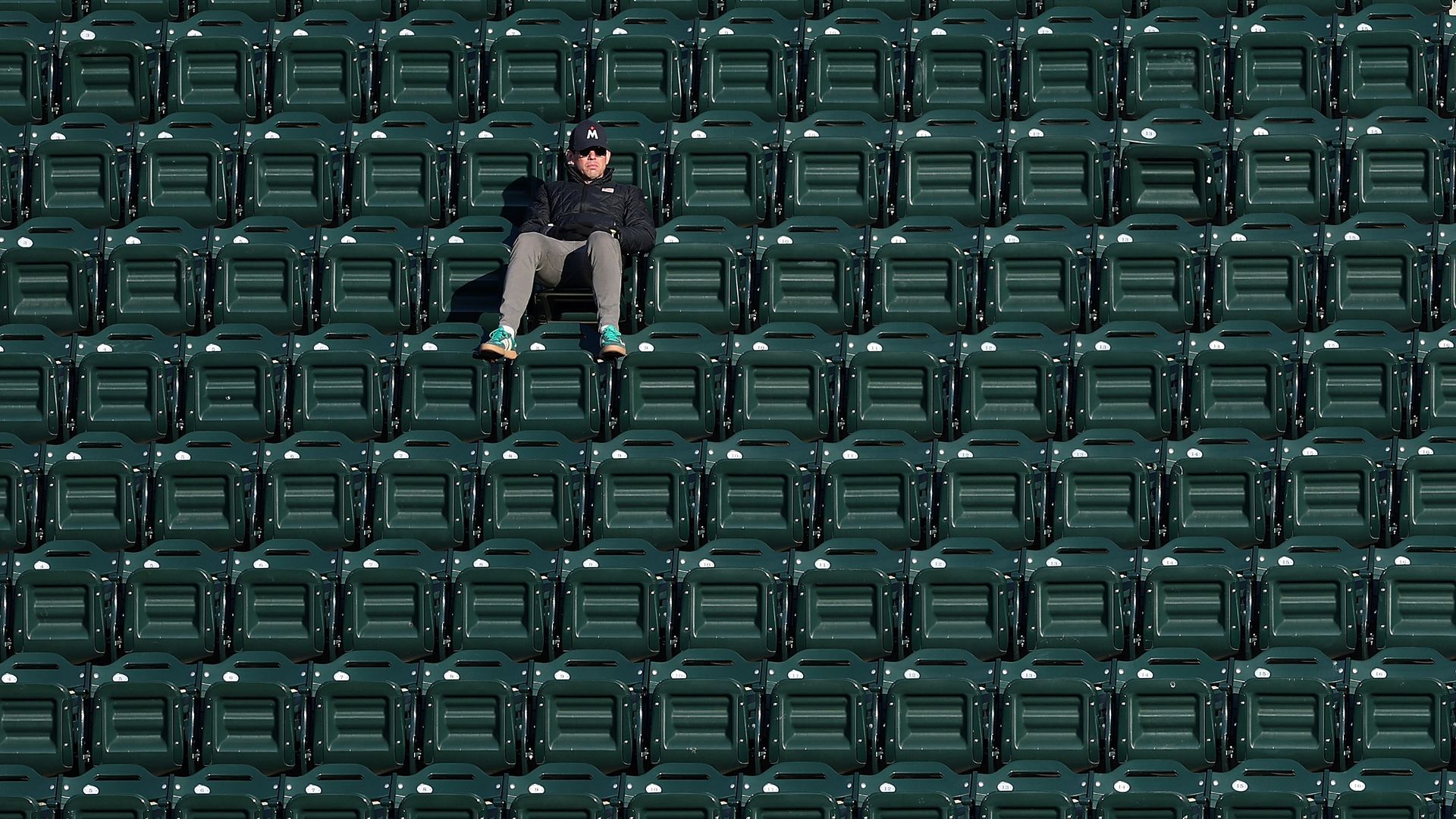 A fan in a Minnesota Twins cap watching a game in a ballpark surrounded by roughly 100 empty stadium seats