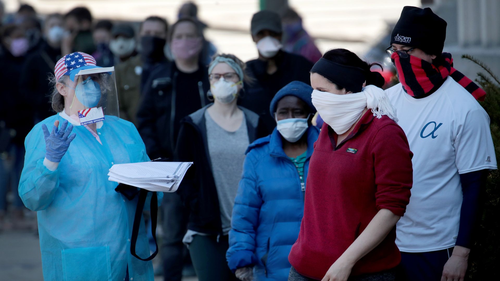 A Wisconsin poll worker wearing PPE guides people through a line. Photo: Scott Olson/Getty Images