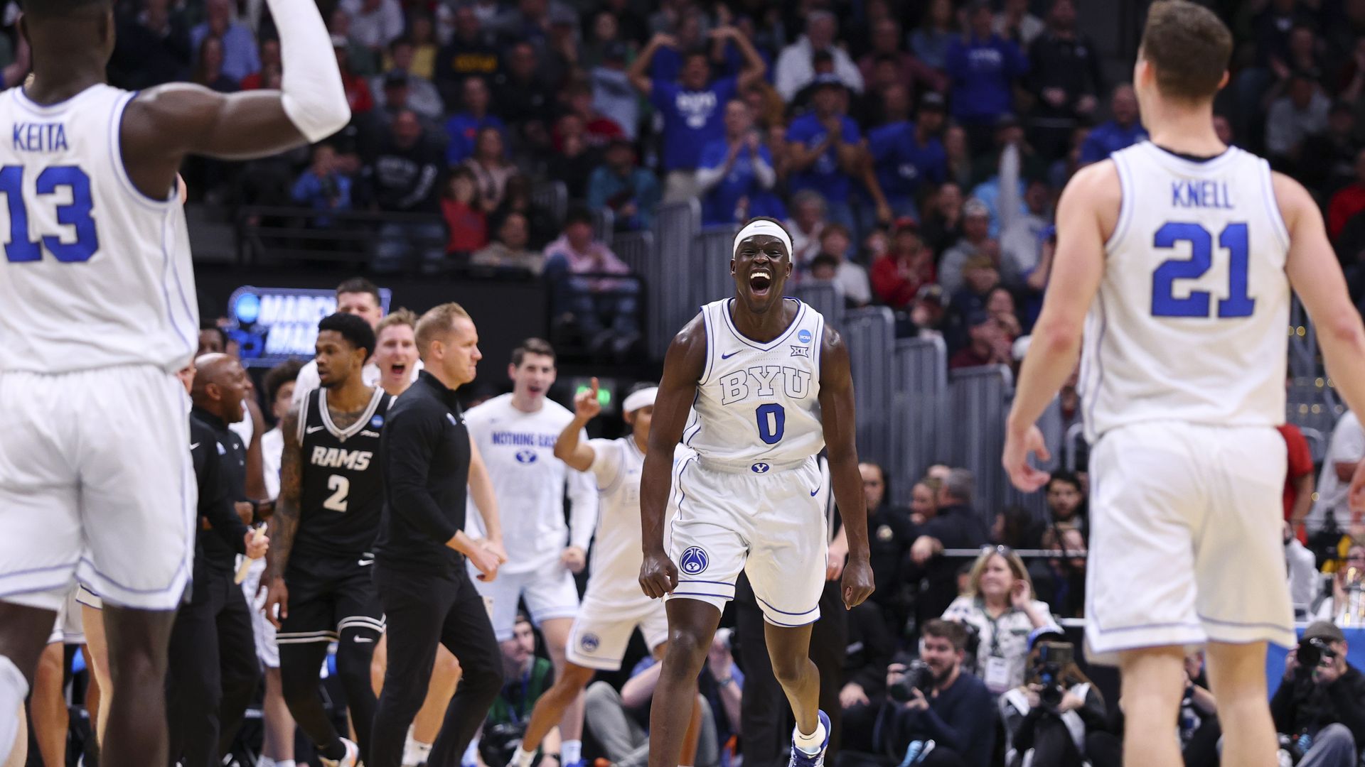 A man in a white basketball uniform reacts with joy during a game
