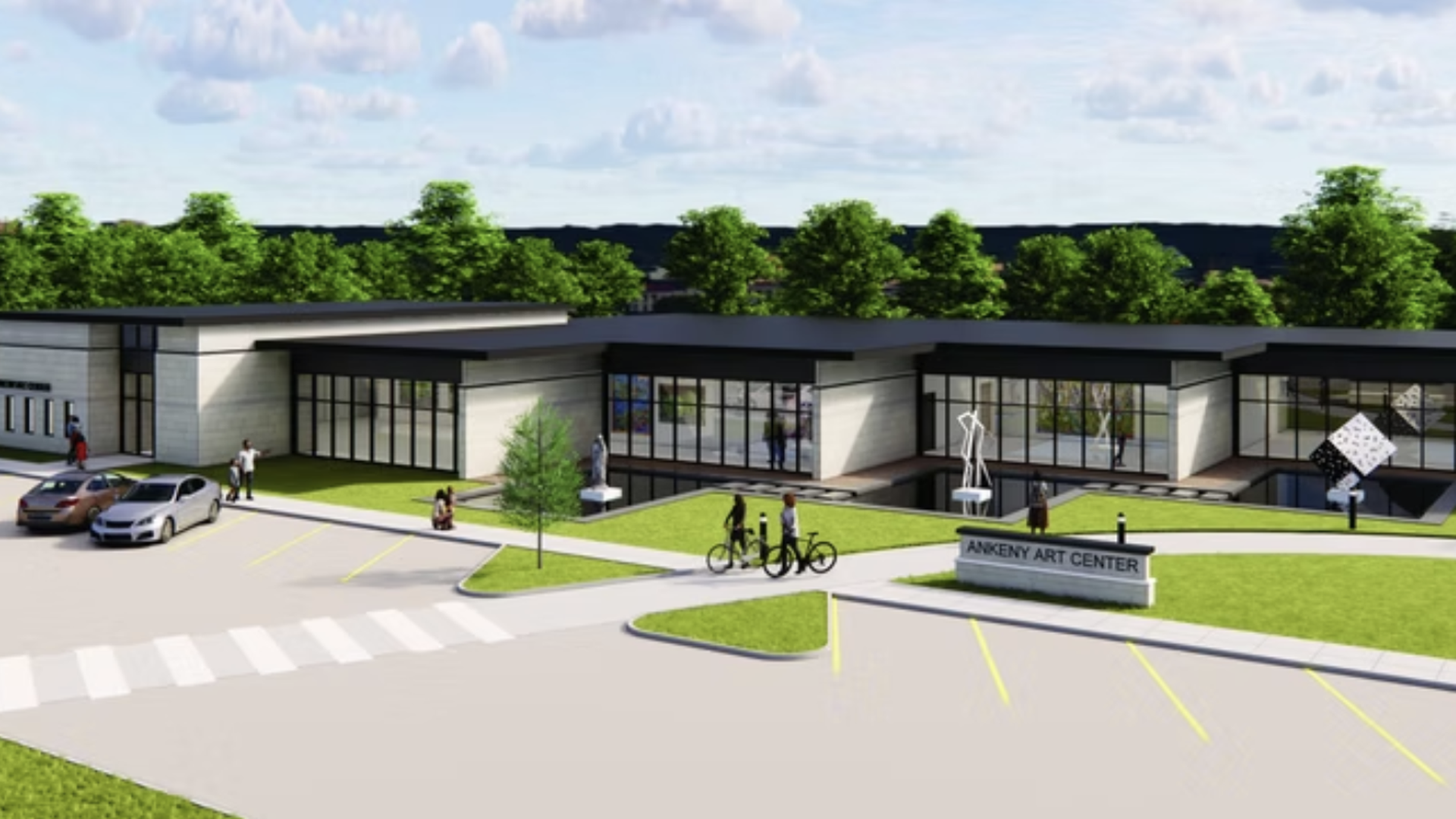 Modern, single-story art center with large glass walls, labeled "Ankeny Art Center". In front, a parking lot with yellow lines, pedestrians, cyclists, and sculptures on green lawns under a blue sky.