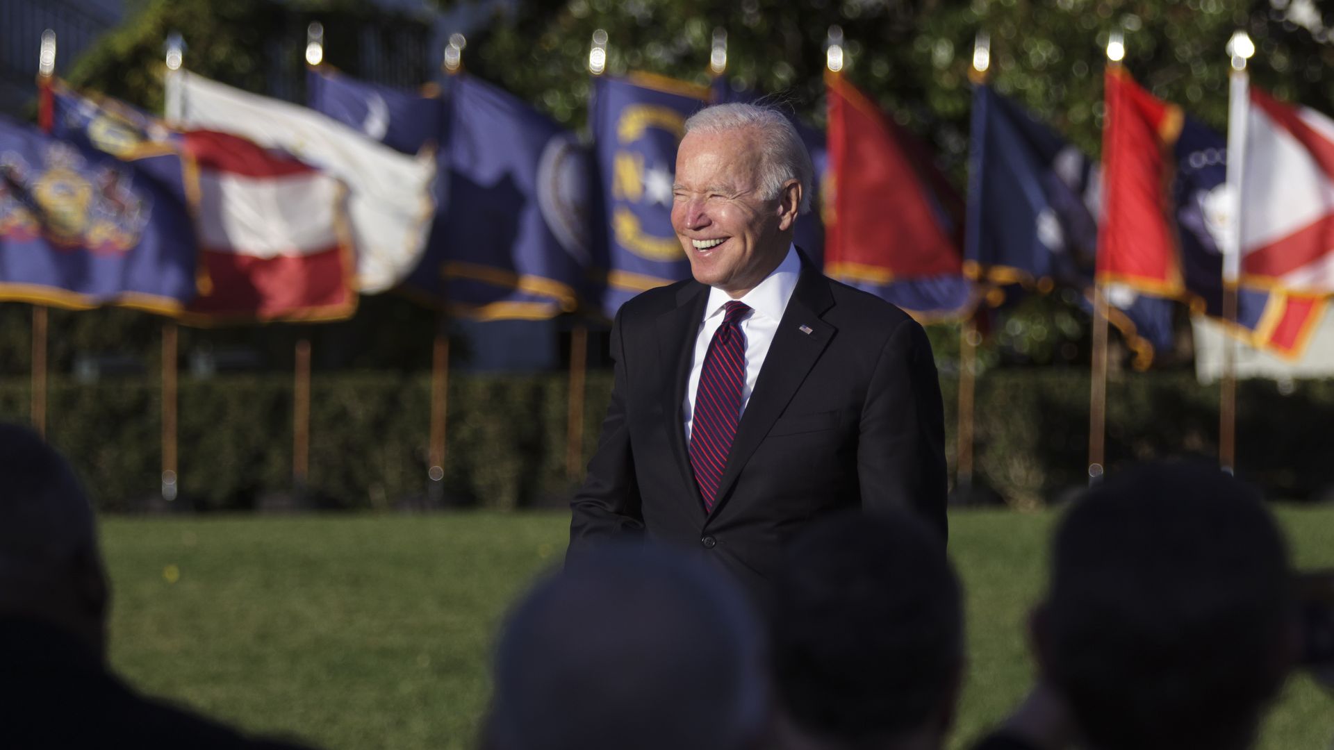 Photo of Joe Biden smiling on the White House lawn in front of an audience