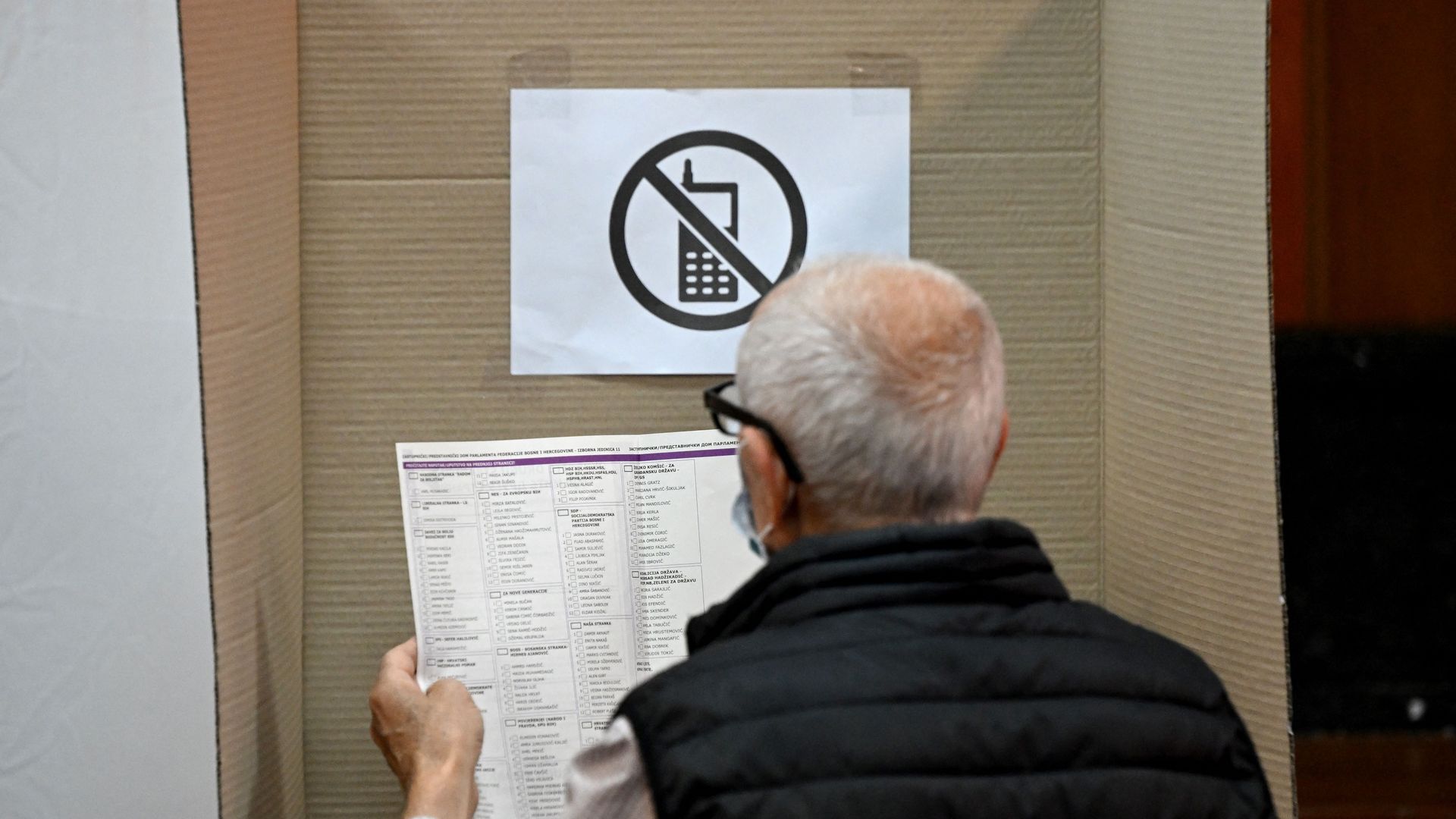A voter reads an election ballot at a polling station 