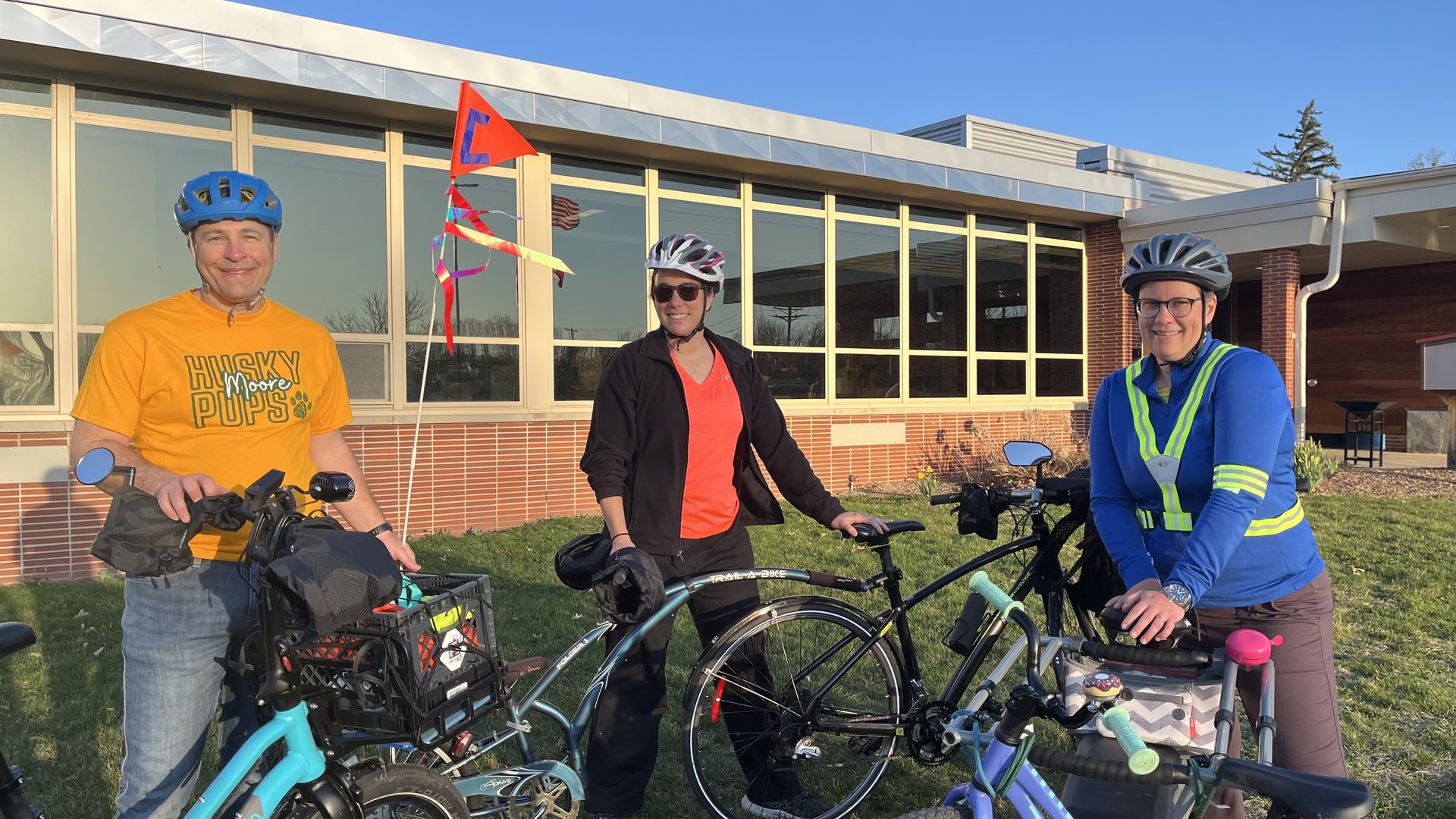Three parents standing outside Moore with their bikes