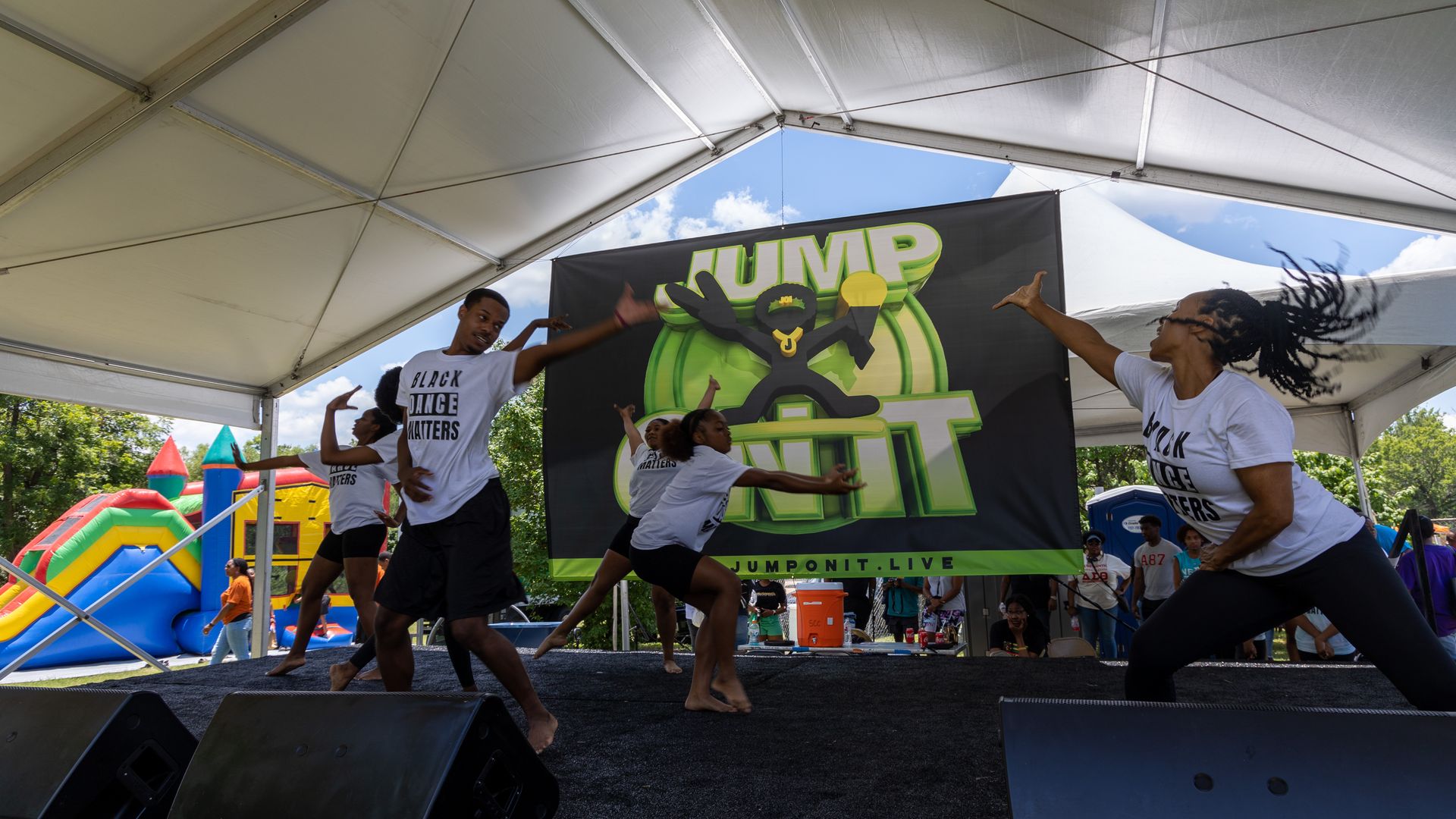 Dancers performing outdoors, beneath a tent.