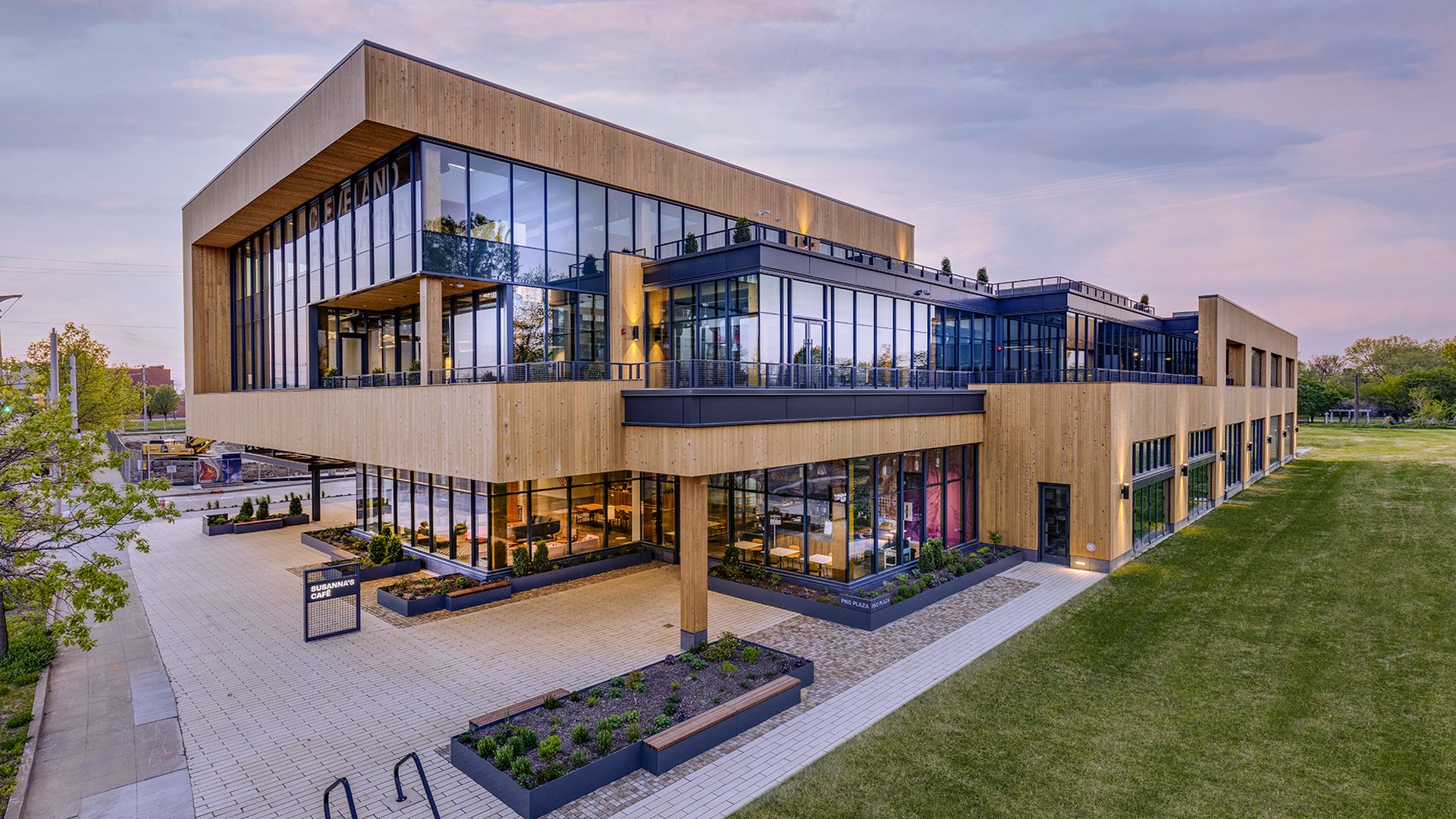 A modern, timber-designed building abutting a lawn, at twilight