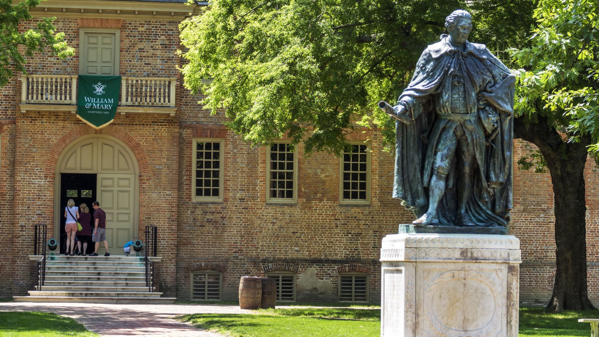 Image of people walking into a large door with a statue in the foreground